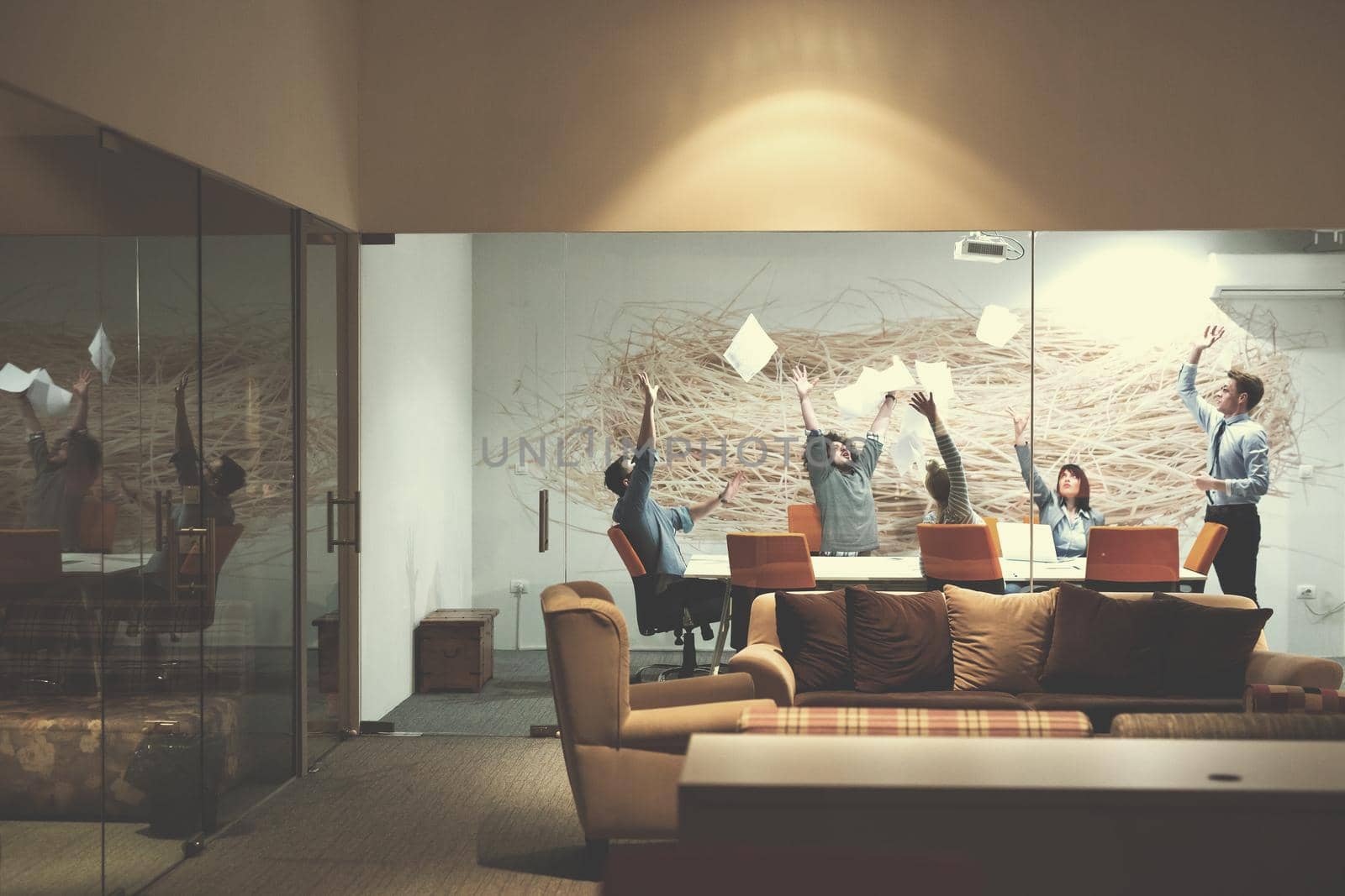 Group of young business people throwing documents and looking happy while celebrating success at their working places in night office