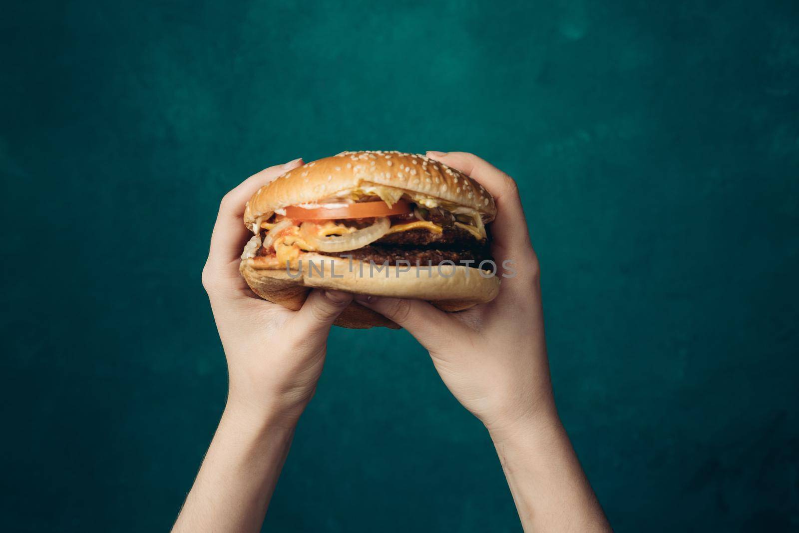 hamburger in hands close-up fast food green background. High quality photo