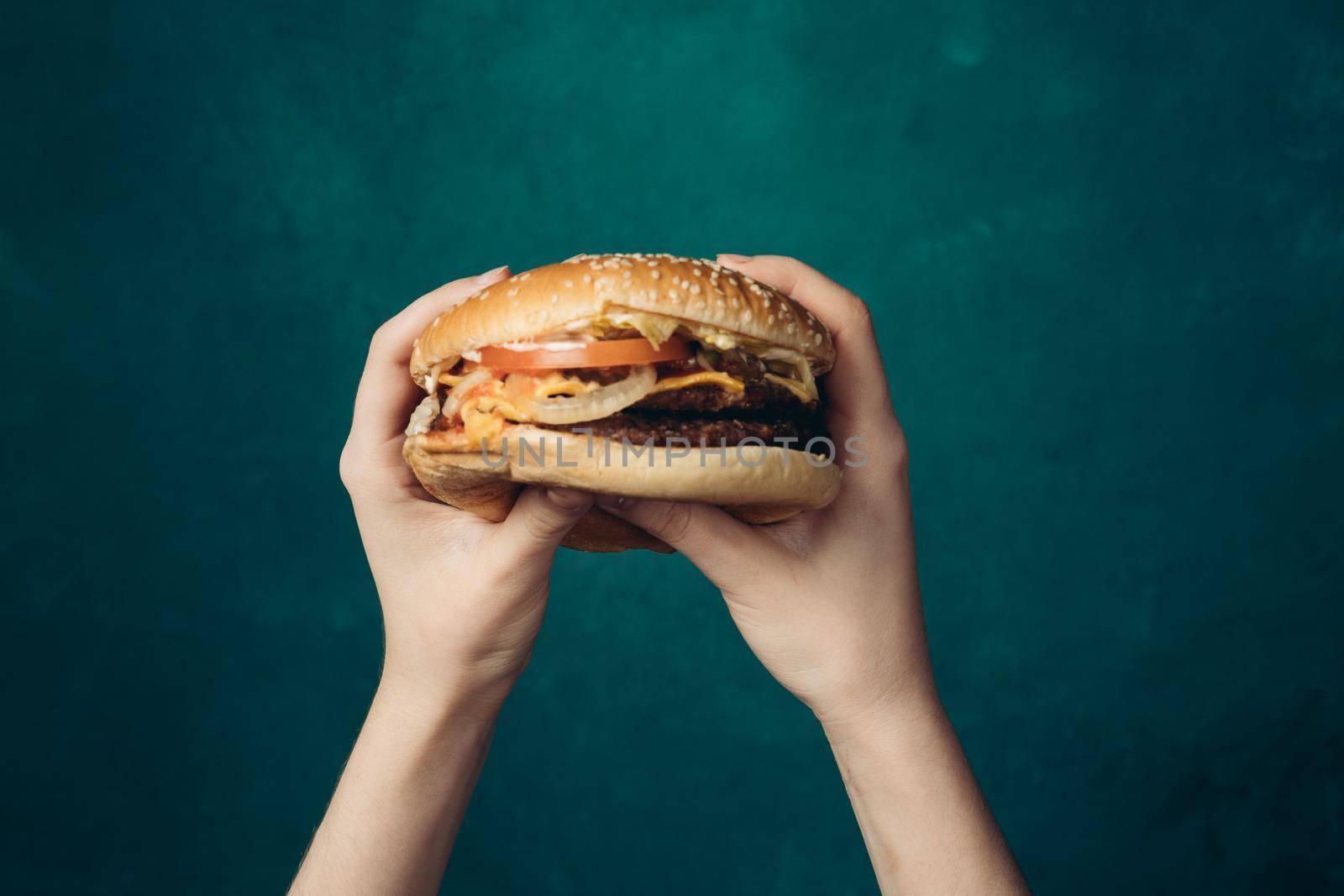 hamburger in hands close-up fast food green background by Vichizh