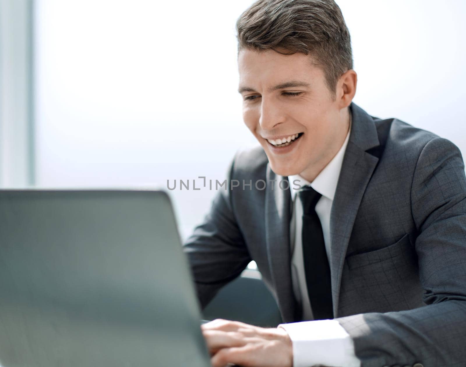 businessman uses laptop sitting at office Desk by asdf