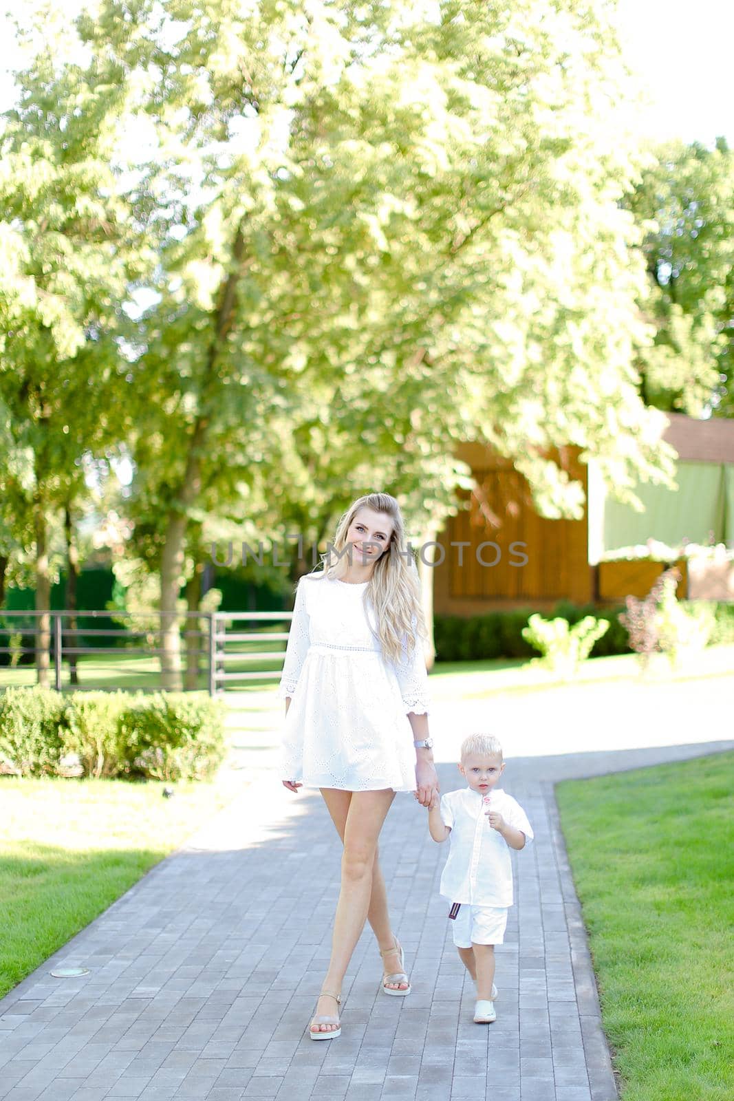 Young european happy mother walking with babe on grass in yard. by sisterspro