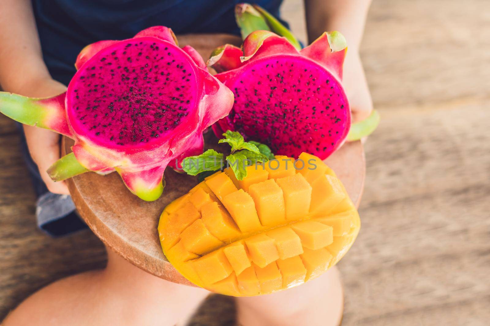 Diced dragon fruit and mango in the hands of the boy.