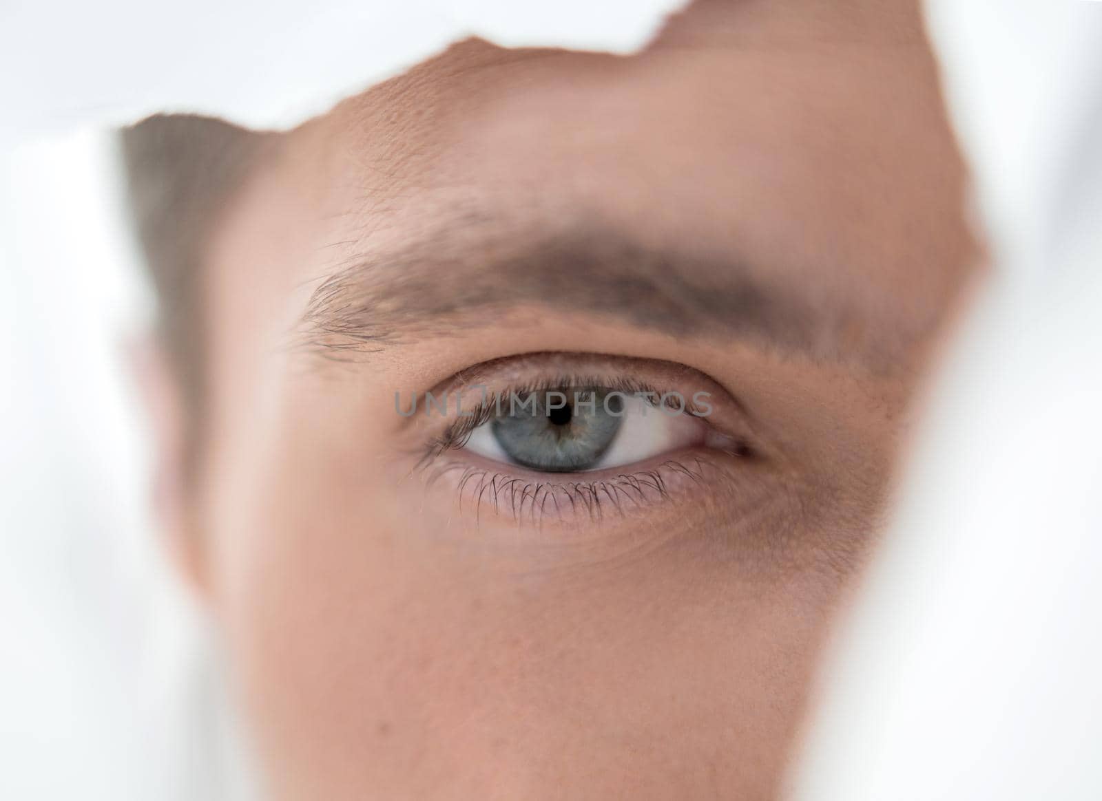 young businessman looking through a hole in the paper wall.photo with copy space