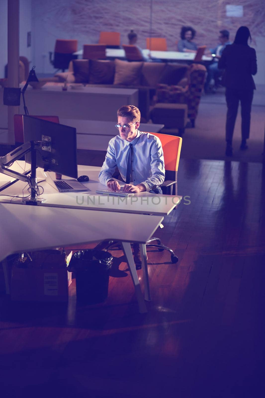 Young man working on computer at night in dark office. The designer works in the later time.