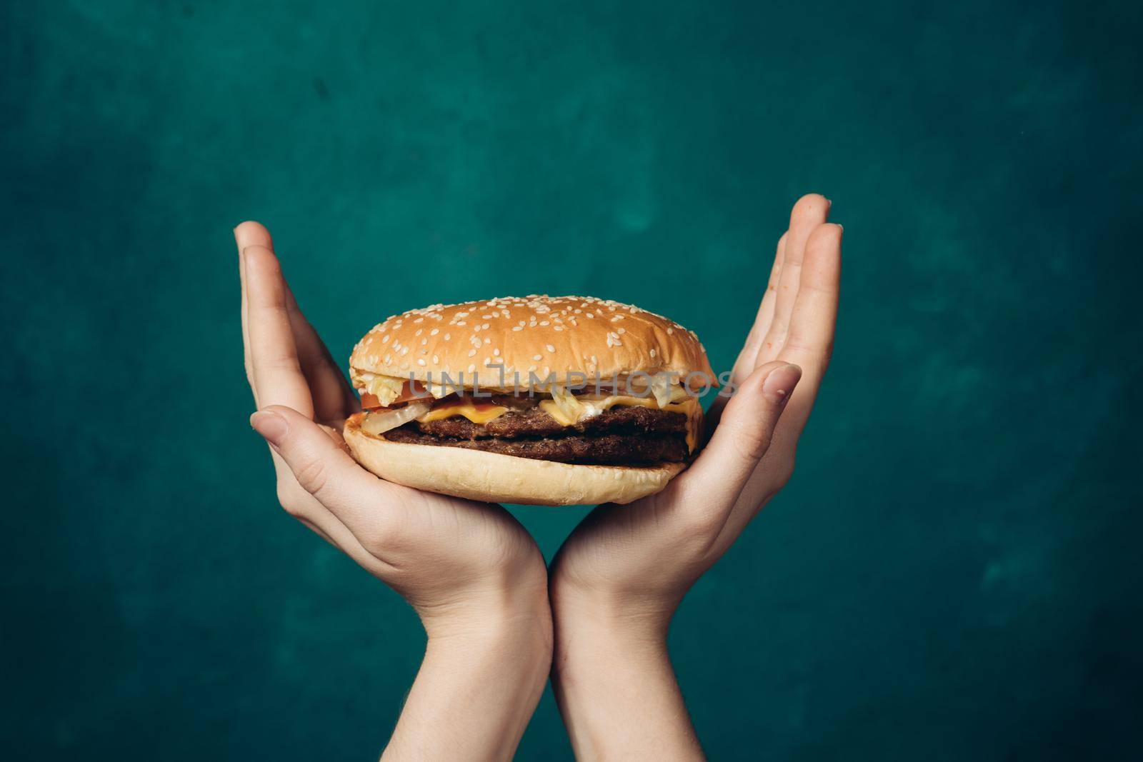 hamburger in hands close-up fast food green background by Vichizh