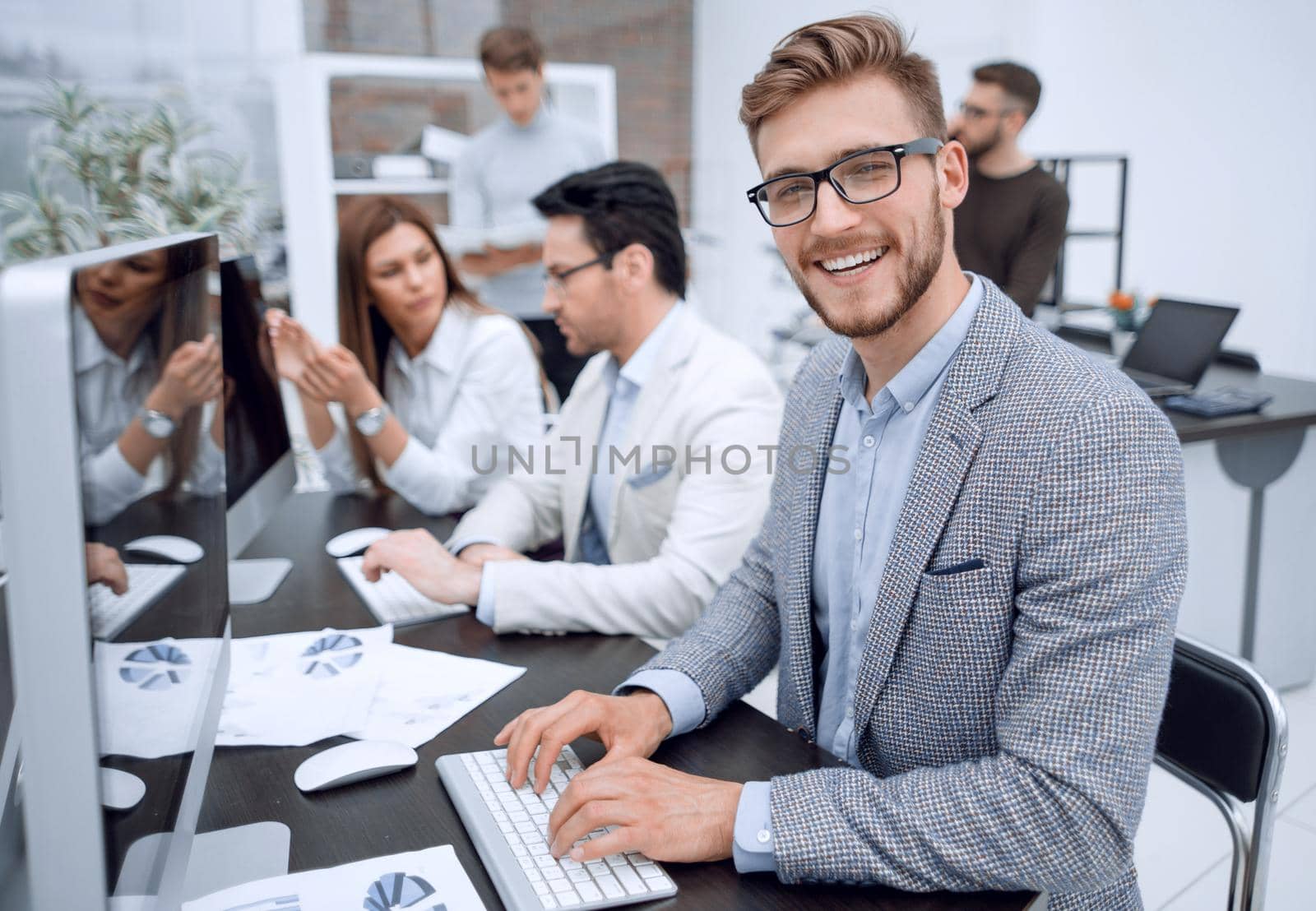 smiling businessman uses a computer to analyze financial data by asdf
