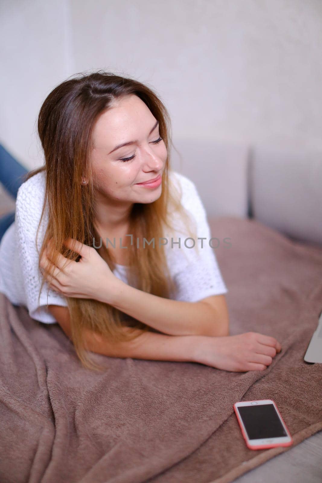 Young woman lying on bed near smartphone. Concept of rest, leisure time and modern technology.