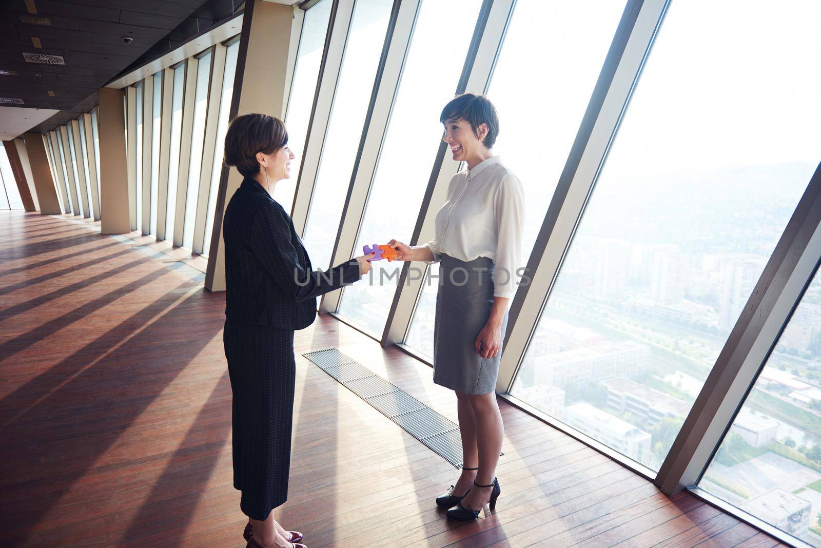 business woman group assembling jigsaw puzzle and represent team support and help concept, top view perspective at modern bright office interior