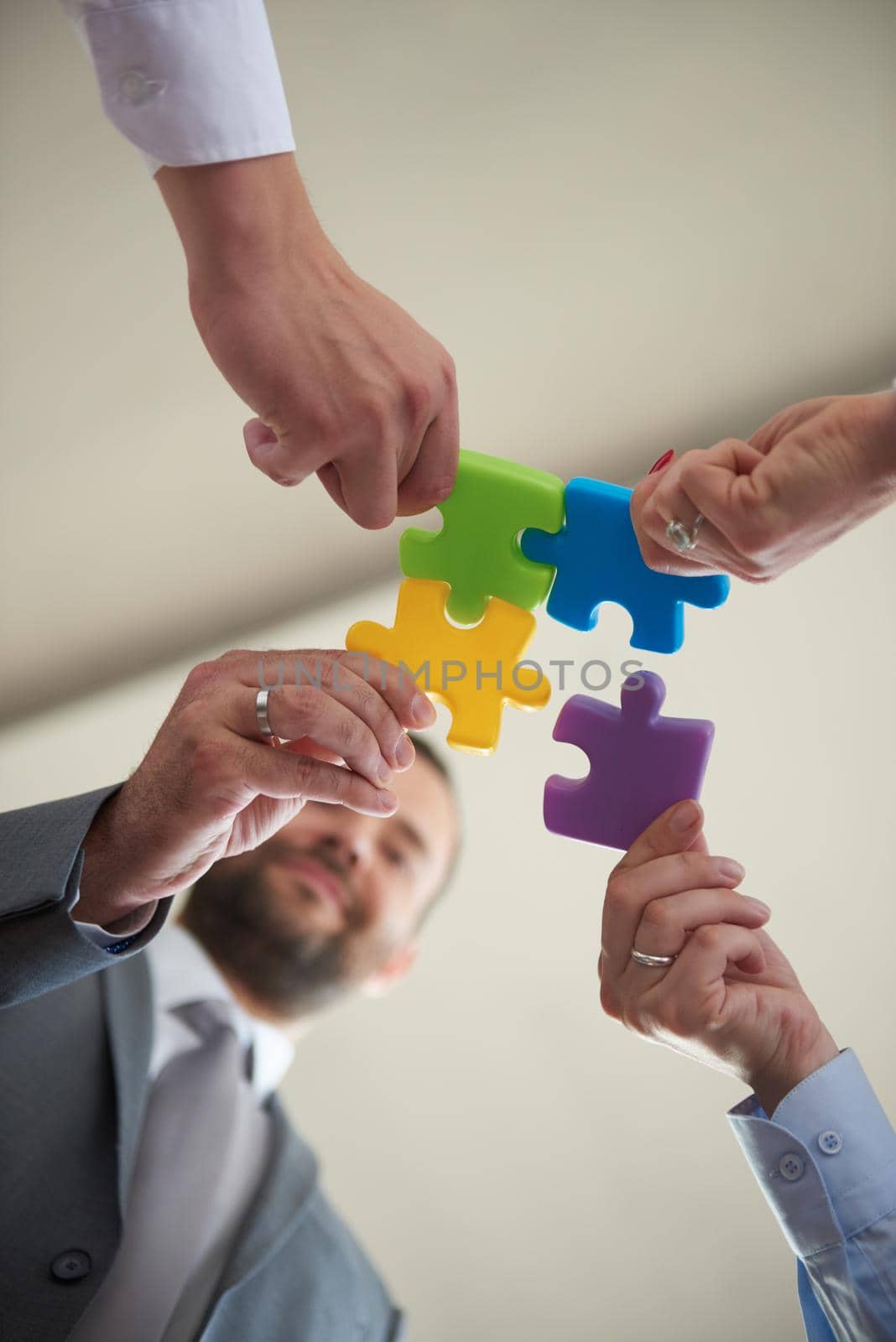 business people group assembling jigsaw puzzle and represent team support and help concept, top view perspective at modern bright office interior