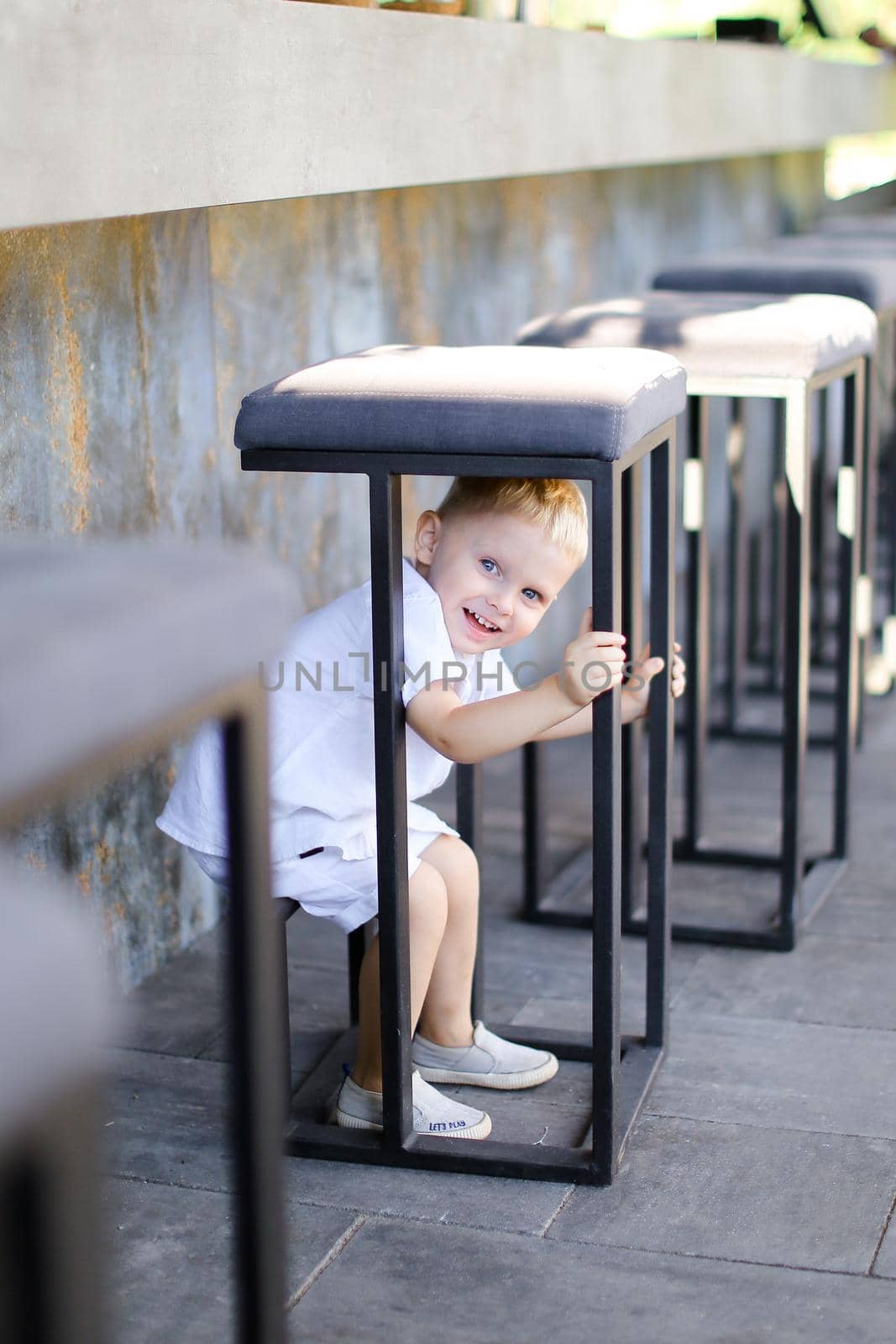 Little male european baby playing outside at street cafe. by sisterspro