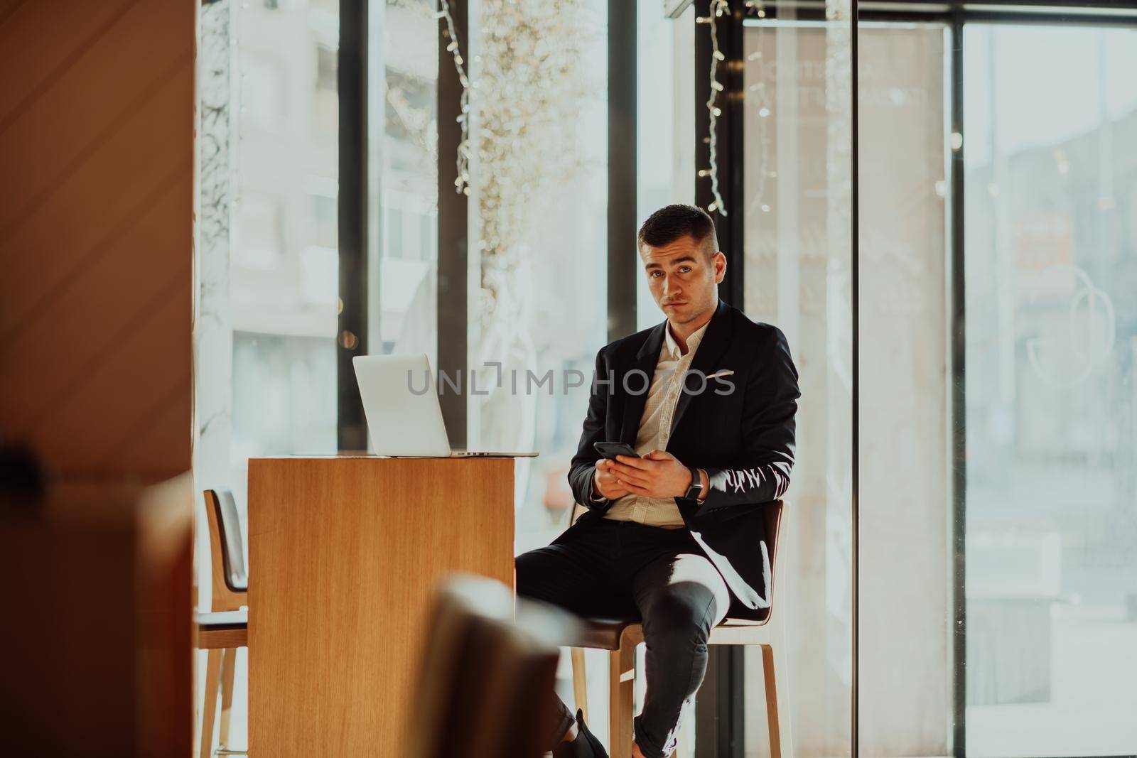 Happy business man sitting at cafeteria with laptop and smartphone by dotshock