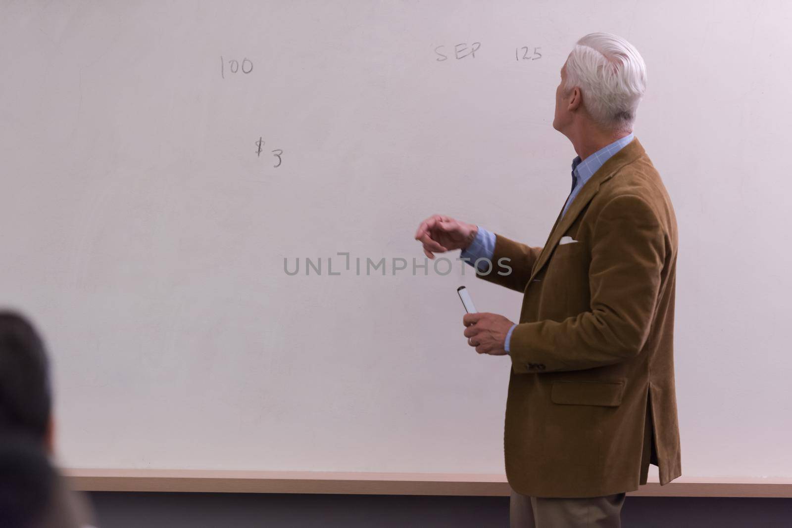 portrait of confident teacher solving problems on whiteboard in classroom