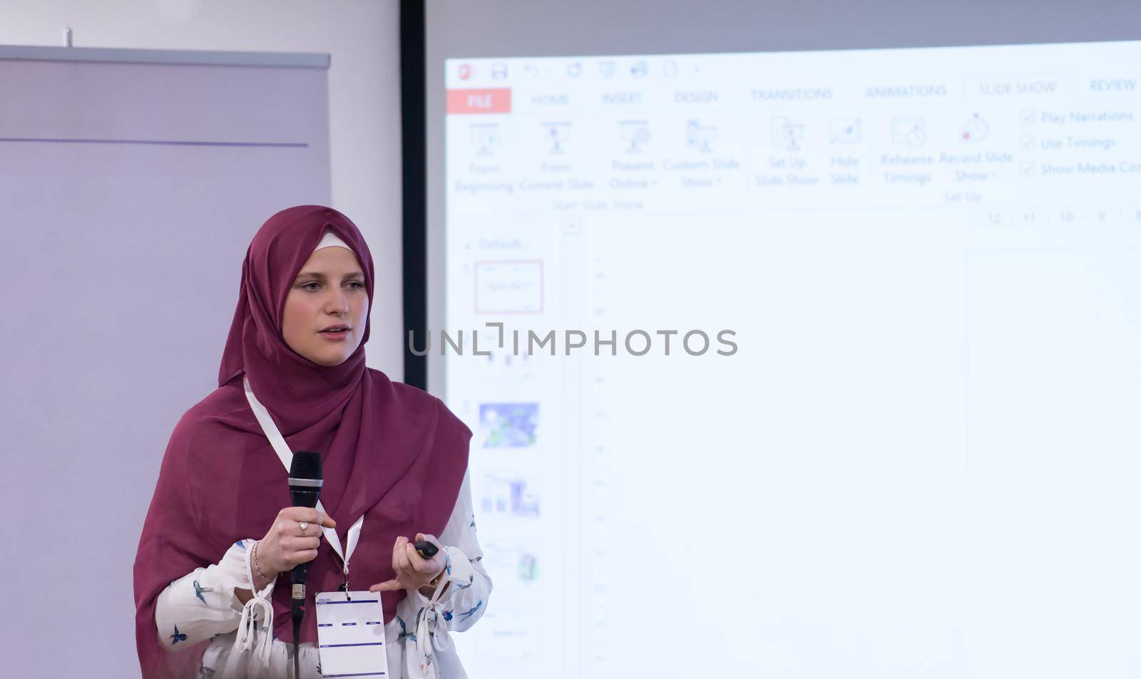 young muslim businesswoman with red scarf at business conference room giving public presentations. Audience at the conference hall. Entrepreneurship club