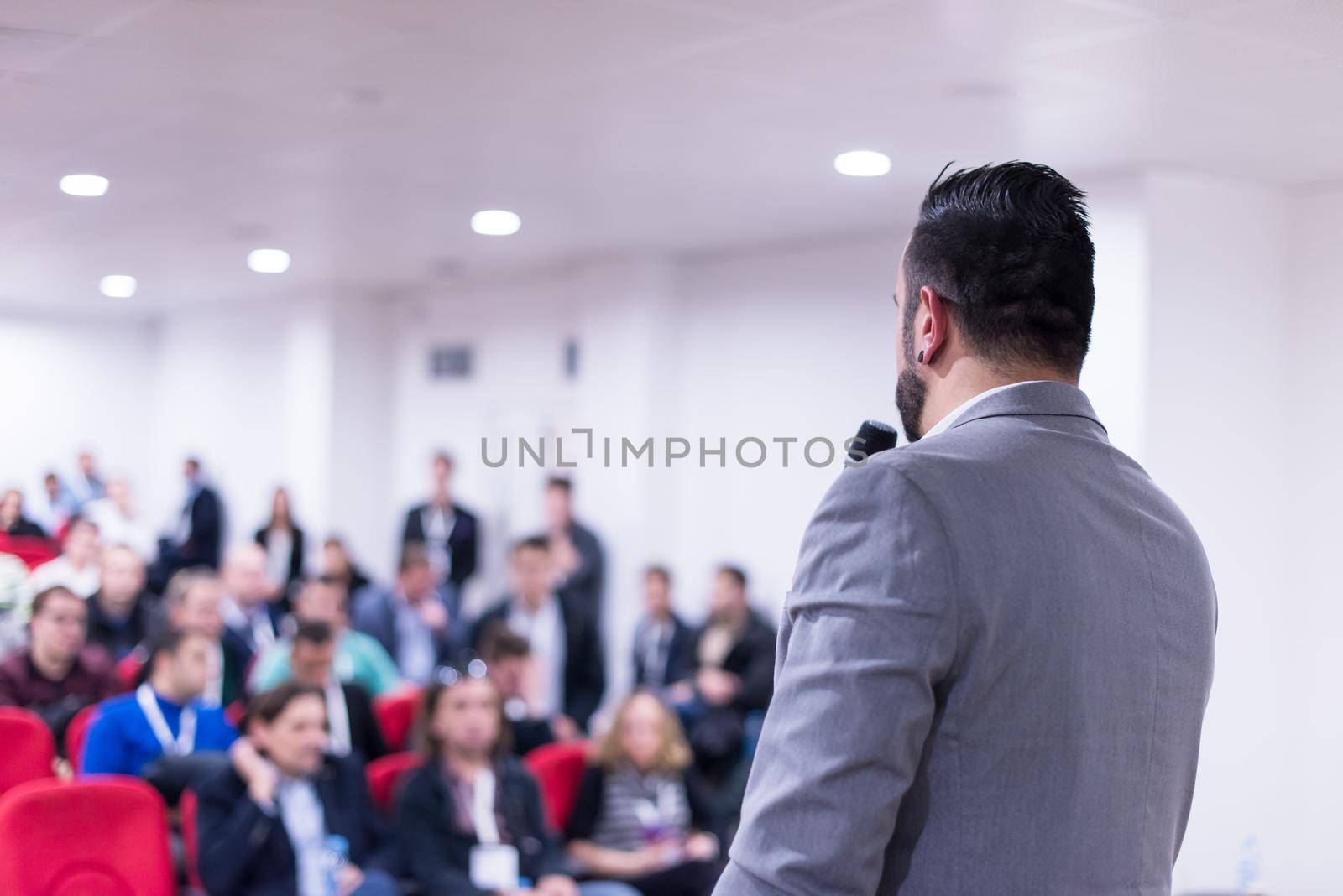 rear view of young successful businessman at business conference room with public giving presentations. Audience at the conference hall. Entrepreneurship club