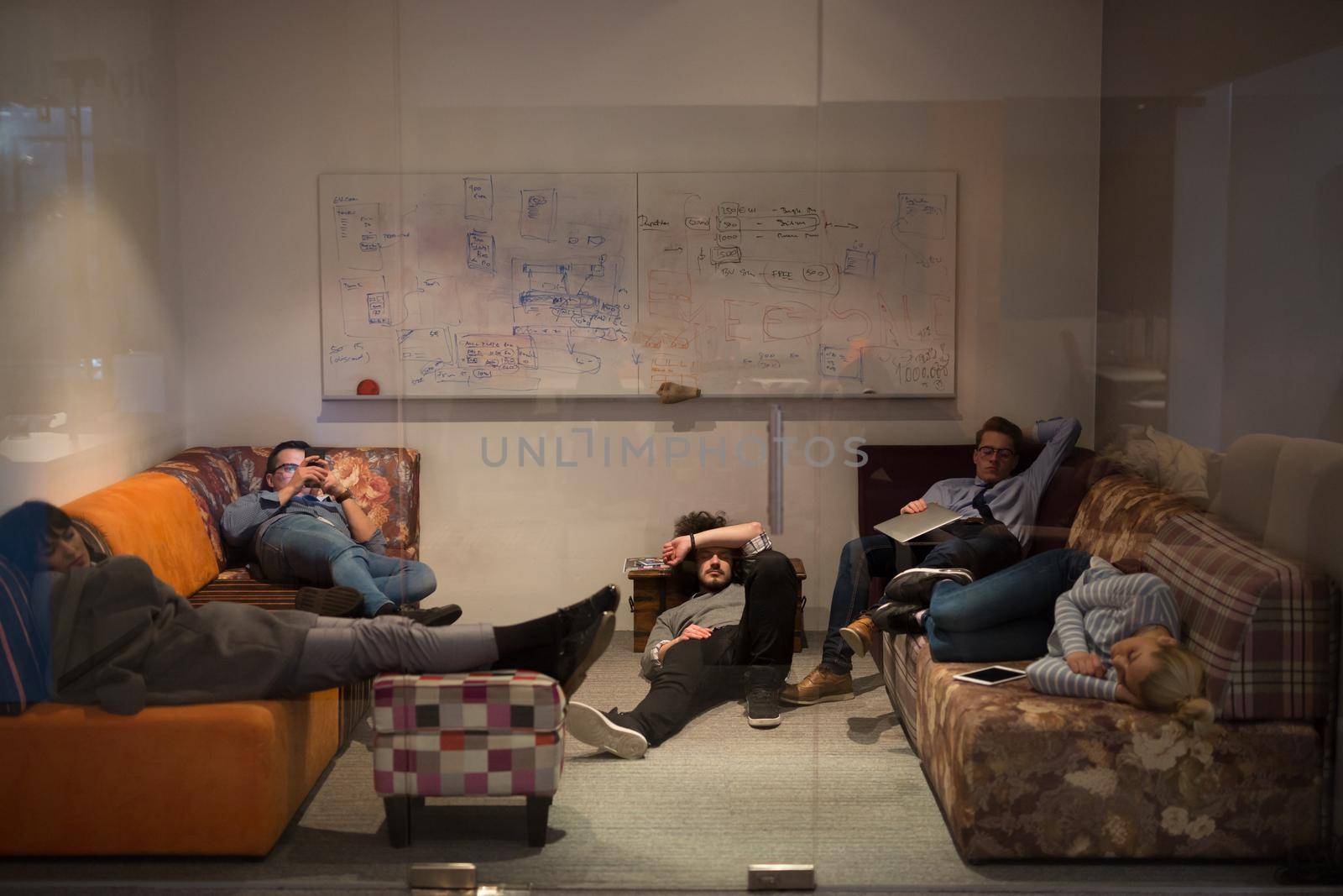 software developers sleeping on sofa in creative startup office by dotshock