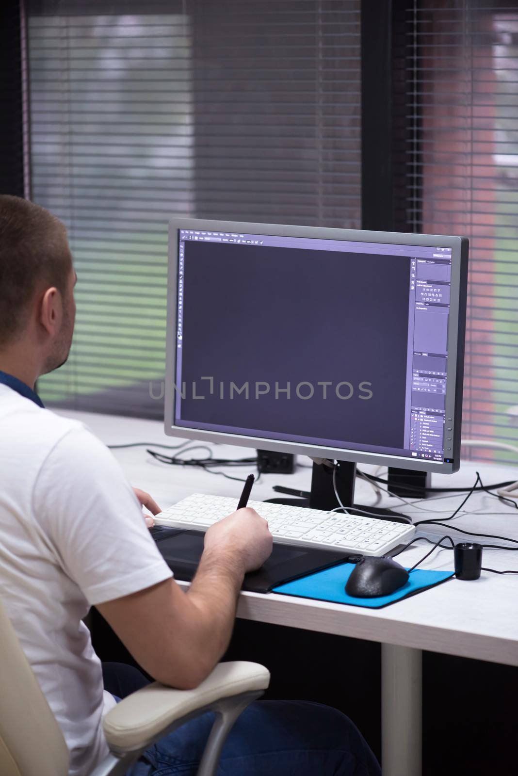 creative worker, photo editor working on graphic tablet at his desktop computer at small startup office