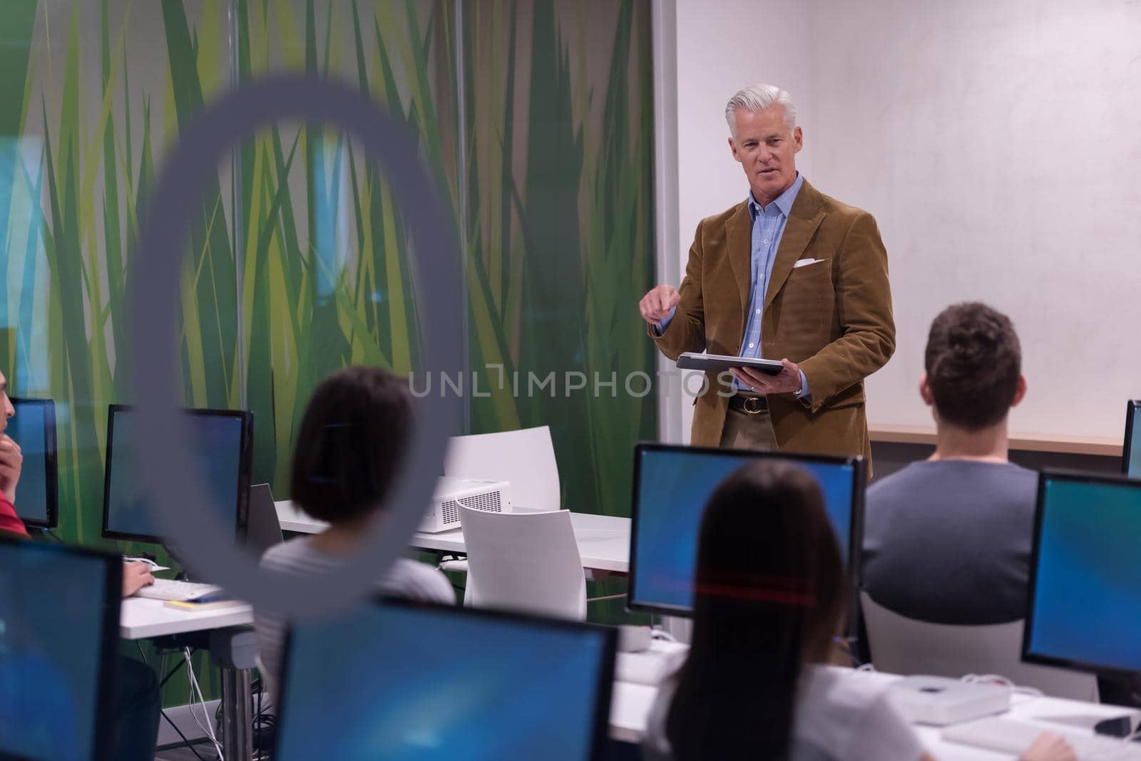 handsome mature teacher and students in computer lab classroom