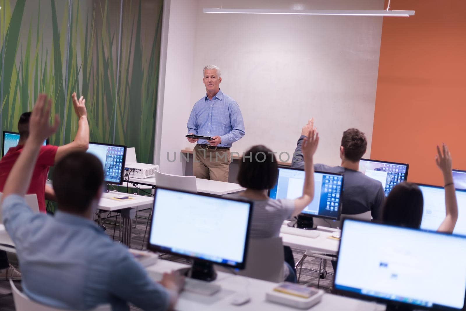 handsome mature teacher and students in computer lab classroom