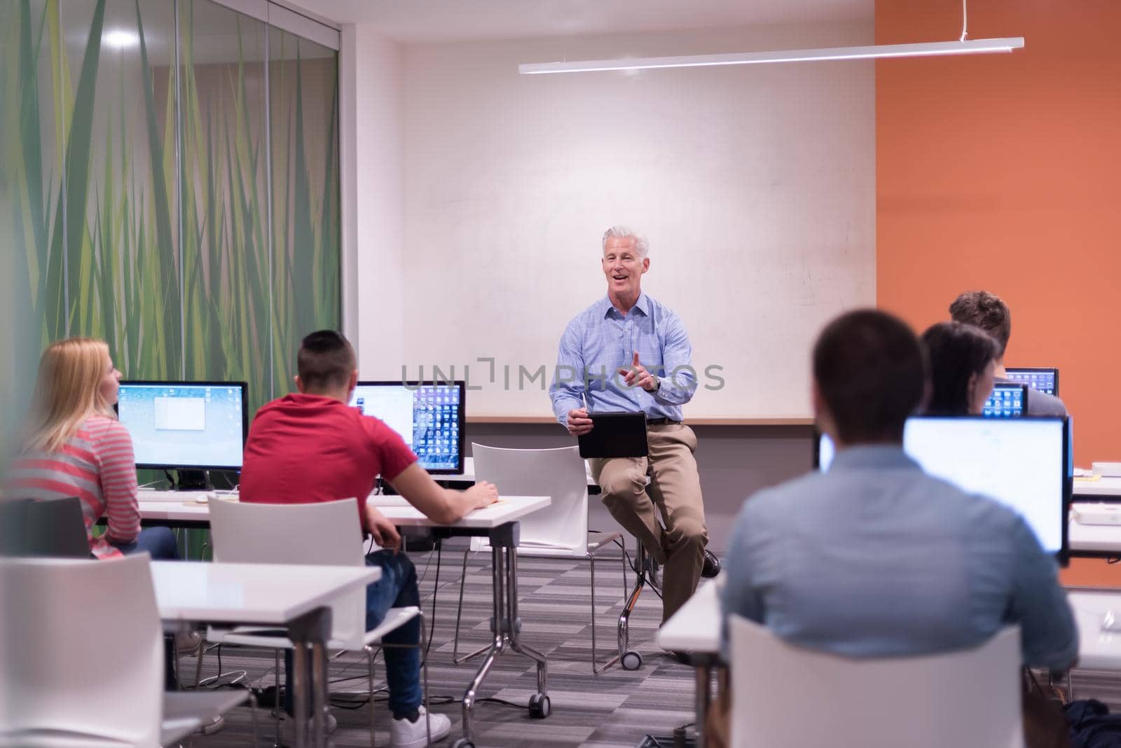 handsome mature teacher and students in computer lab classroom