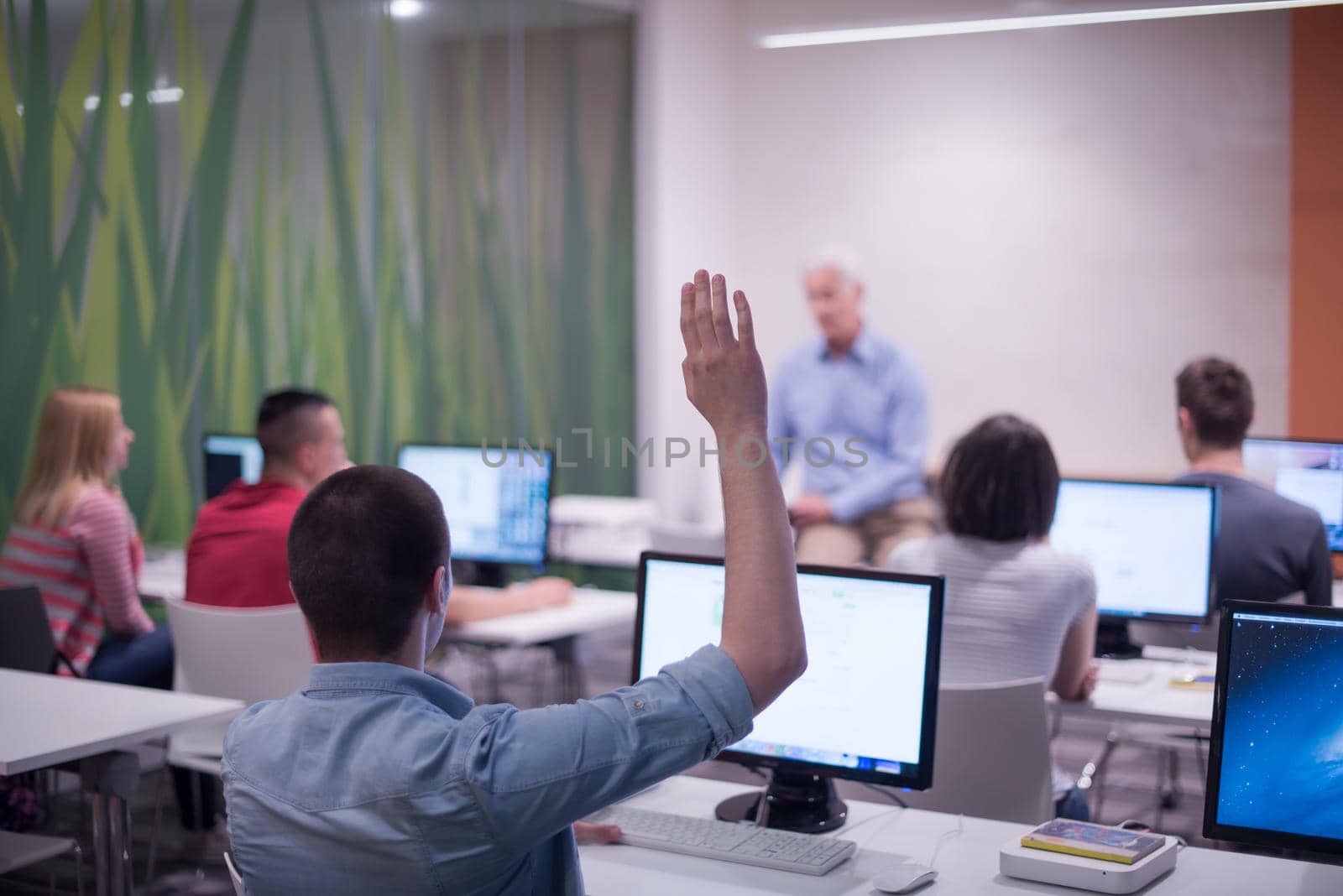 student answering a question in classroom, mature teacher and students in computer lab classroom