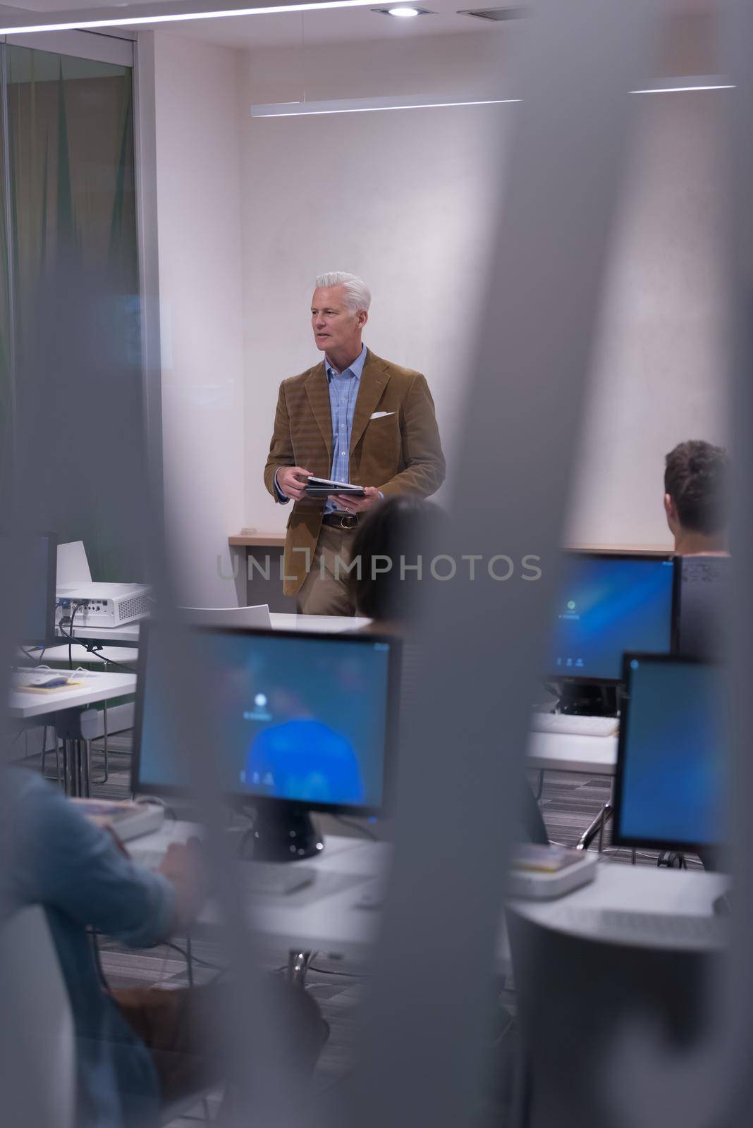 handsome mature teacher and students in computer lab classroom