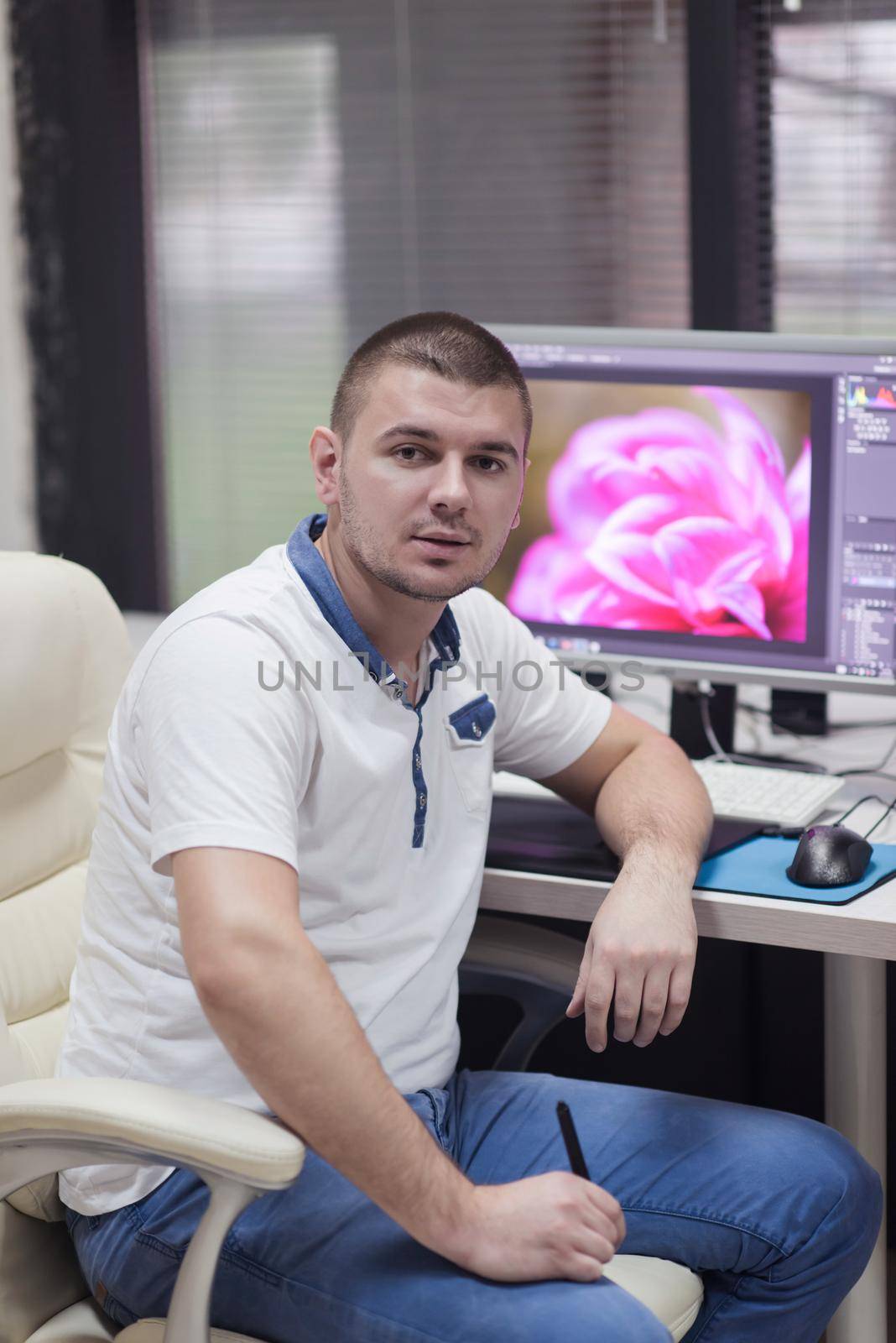 creative worker, photo editor working on graphic tablet at his desktop computer at small startup office