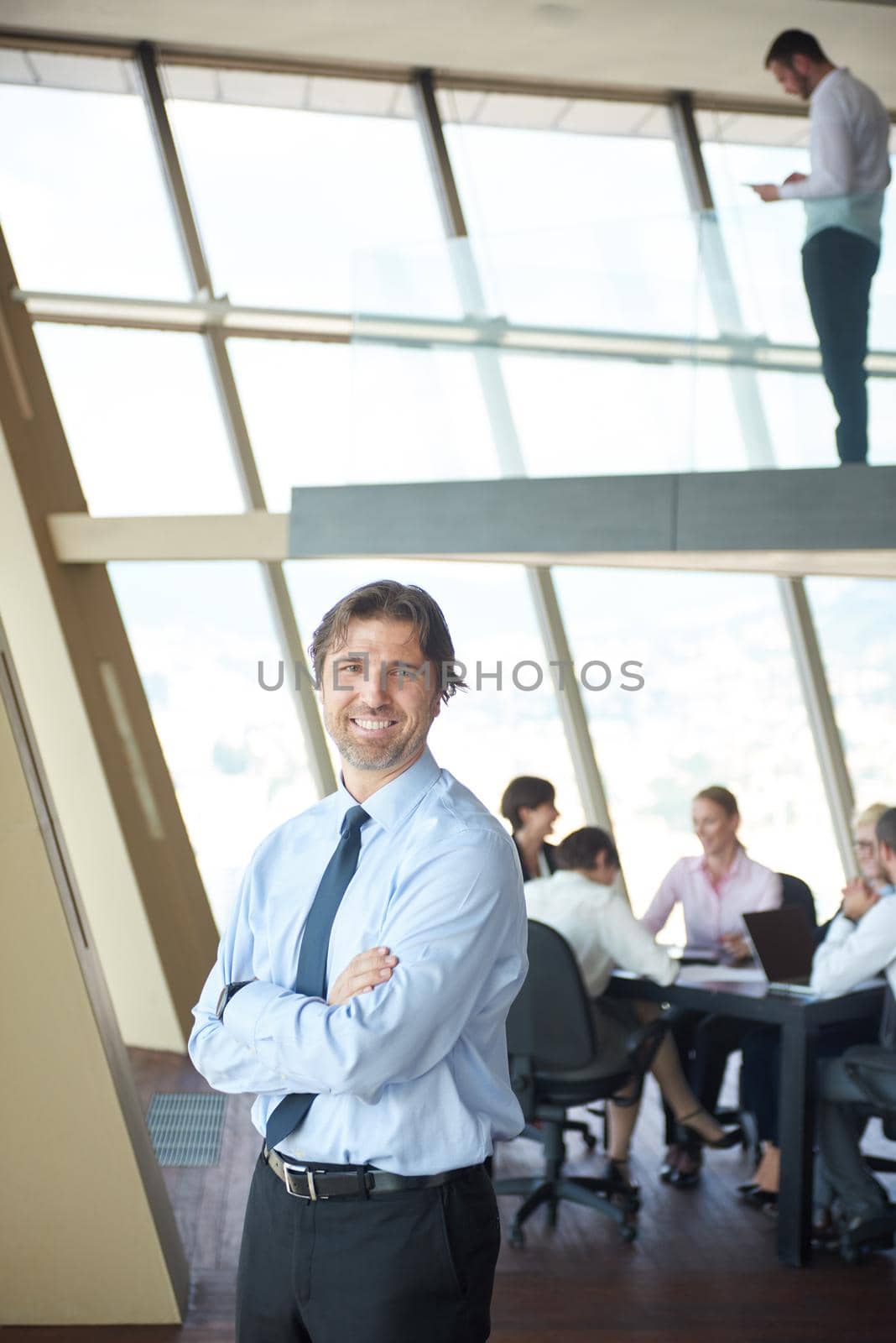 handosme business manportrait  at modern bright office indoors with his team in group working together in background