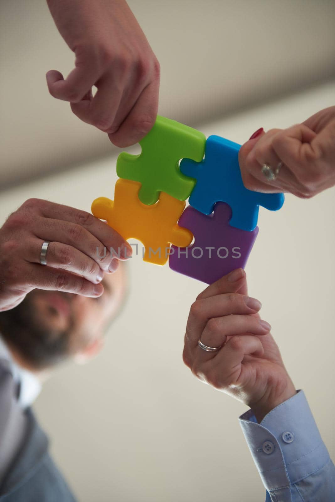 business people group assembling jigsaw puzzle and represent team support and help concept, top view perspective at modern bright office interior