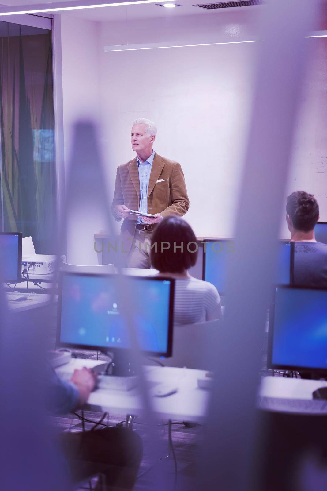 handsome mature teacher and students in computer lab classroom