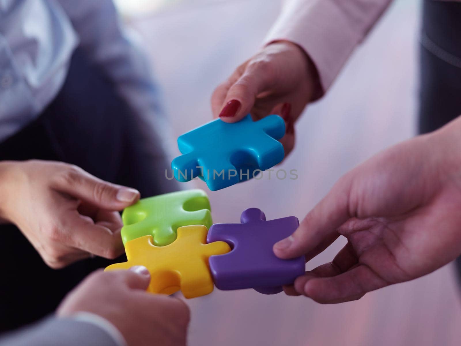 business people group assembling jigsaw puzzle and represent team support and help concept, top view at modern office interior