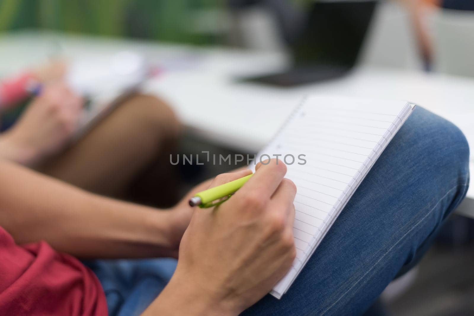 male student taking notes in classroom by dotshock