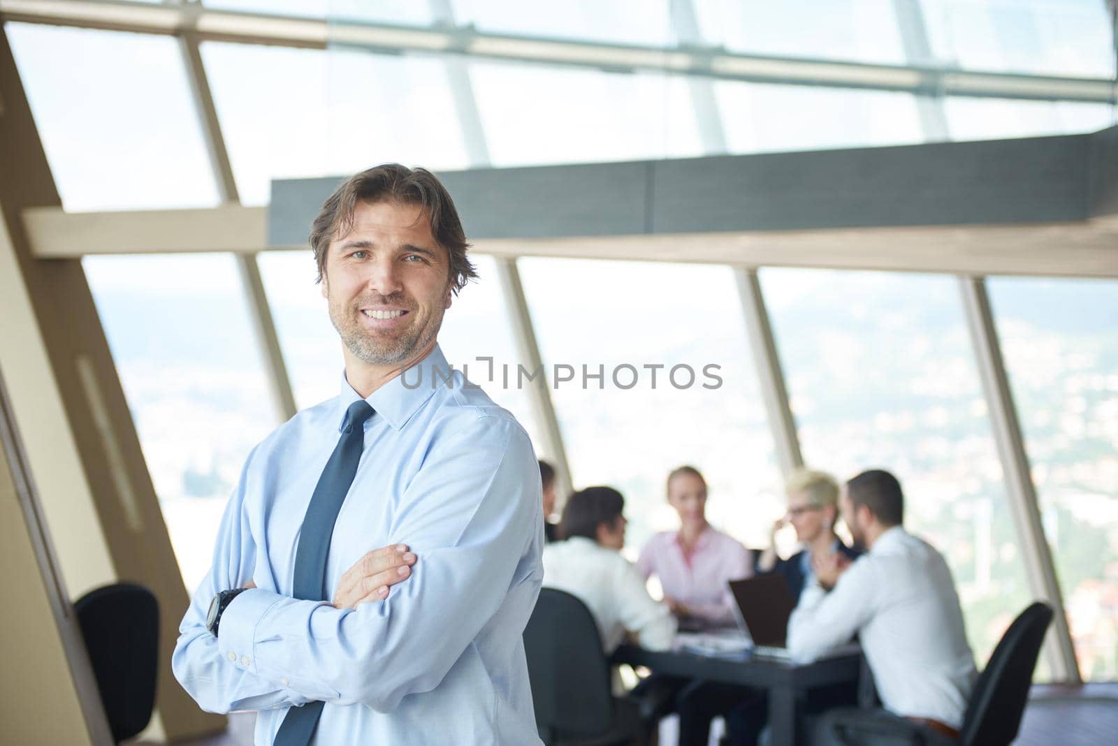 handosme business manportrait  at modern bright office indoors with his team in group working together in background