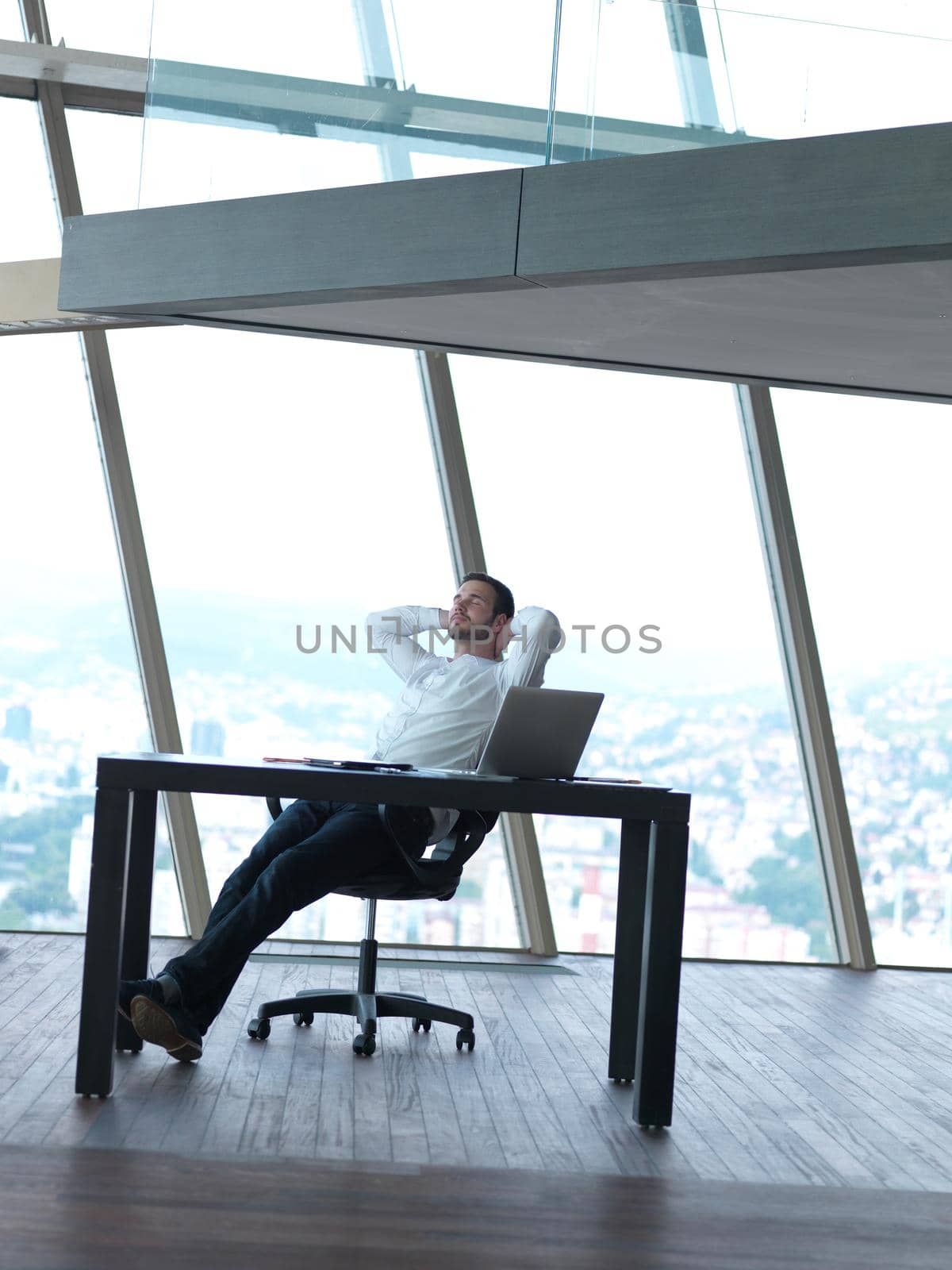 happy young business man work and relax at modern bright office interior, hipster with beard at workplace