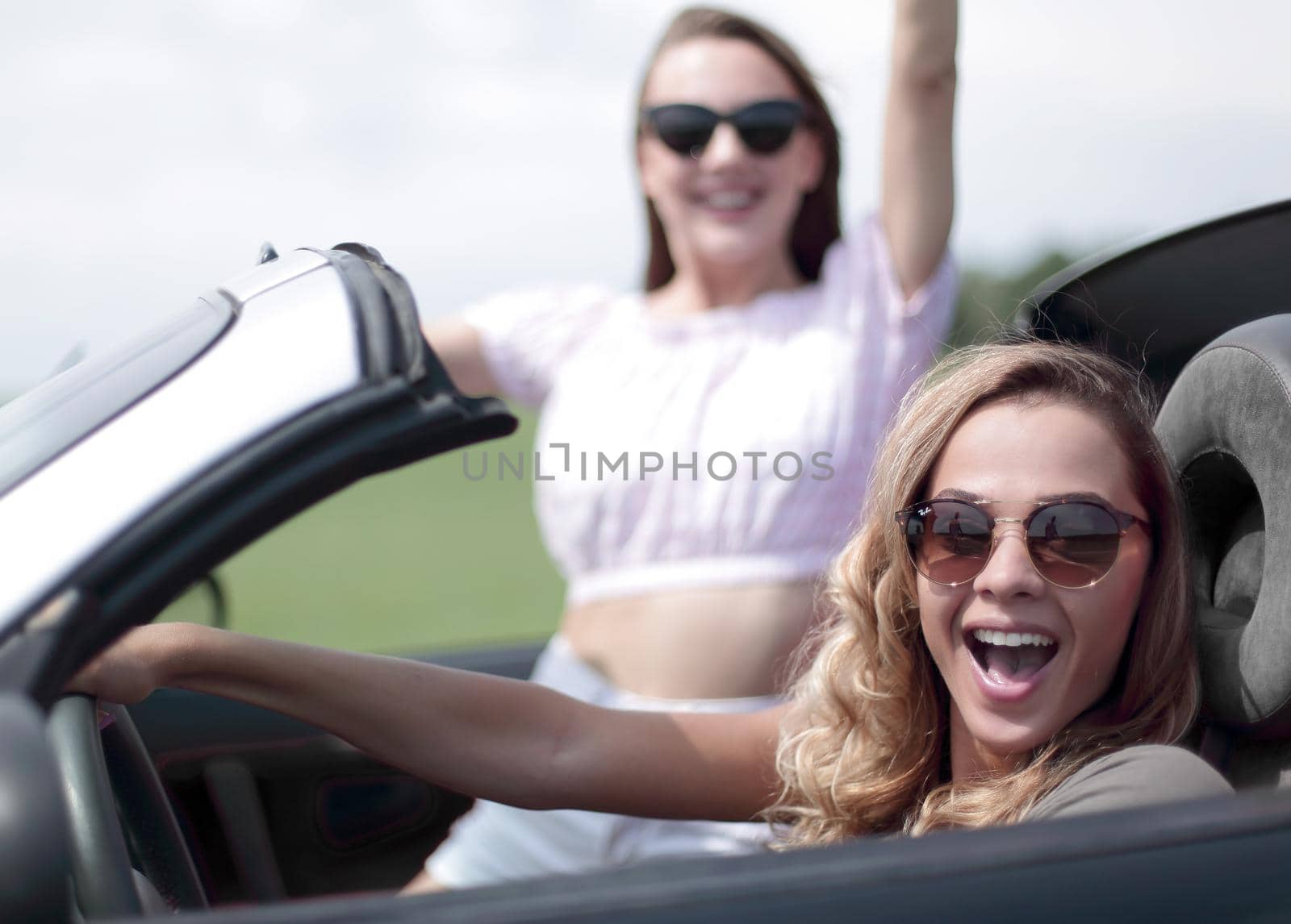 close up.two girlfriends traveling in a convertible car by asdf