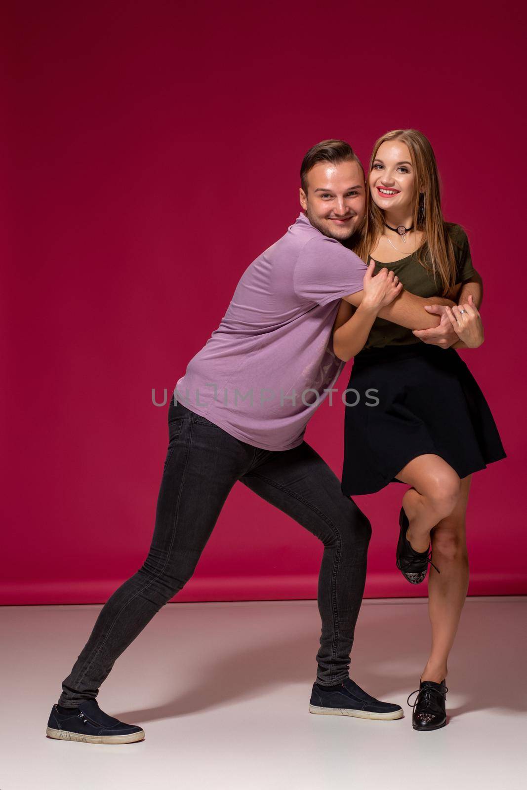 Totally in love. Full length of beautiful young couple embracing and smiling while standing against burgundy background with copy space for your advertisement or written text.