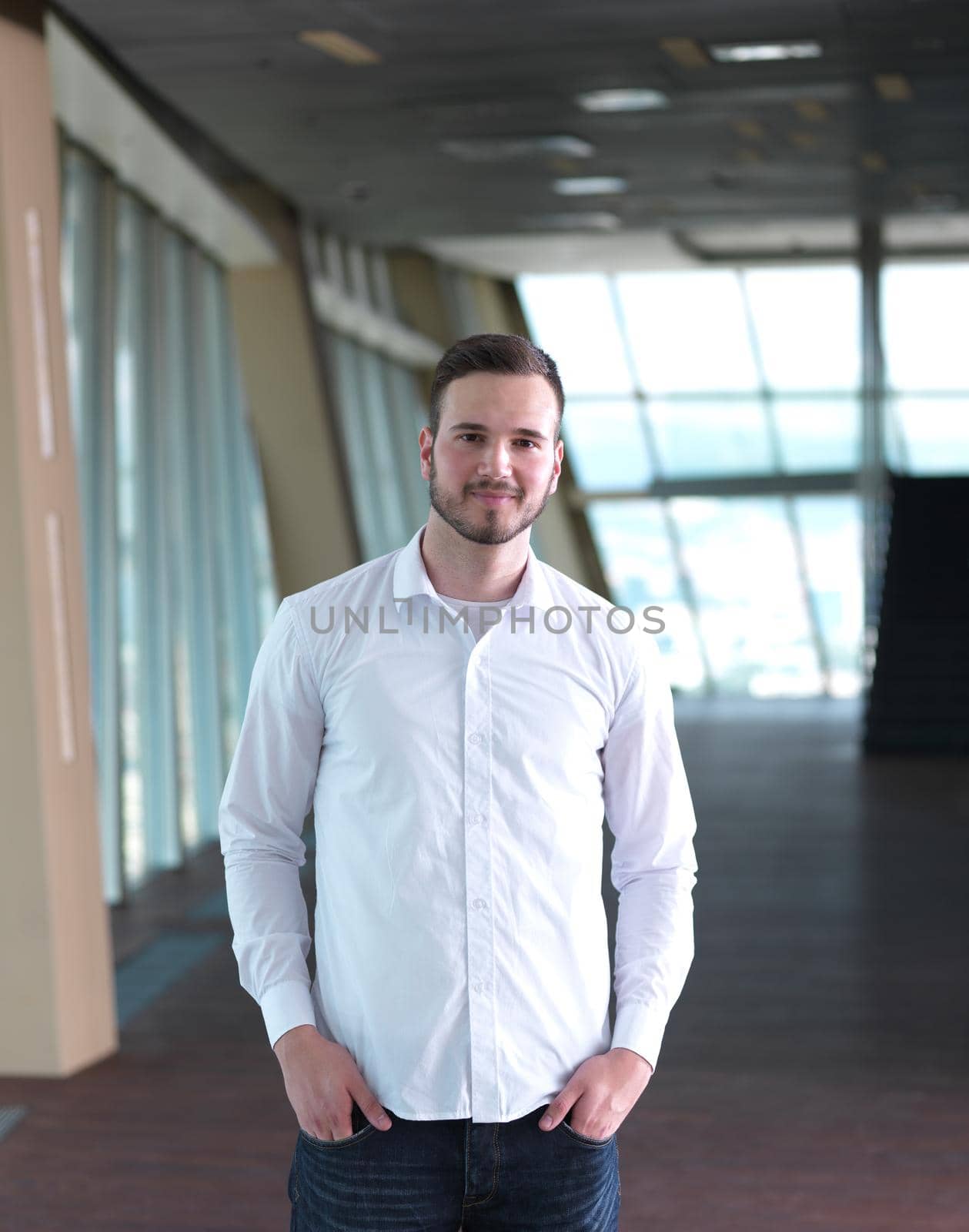 portrait of young handsome hipster business man with beard at modern office space interior