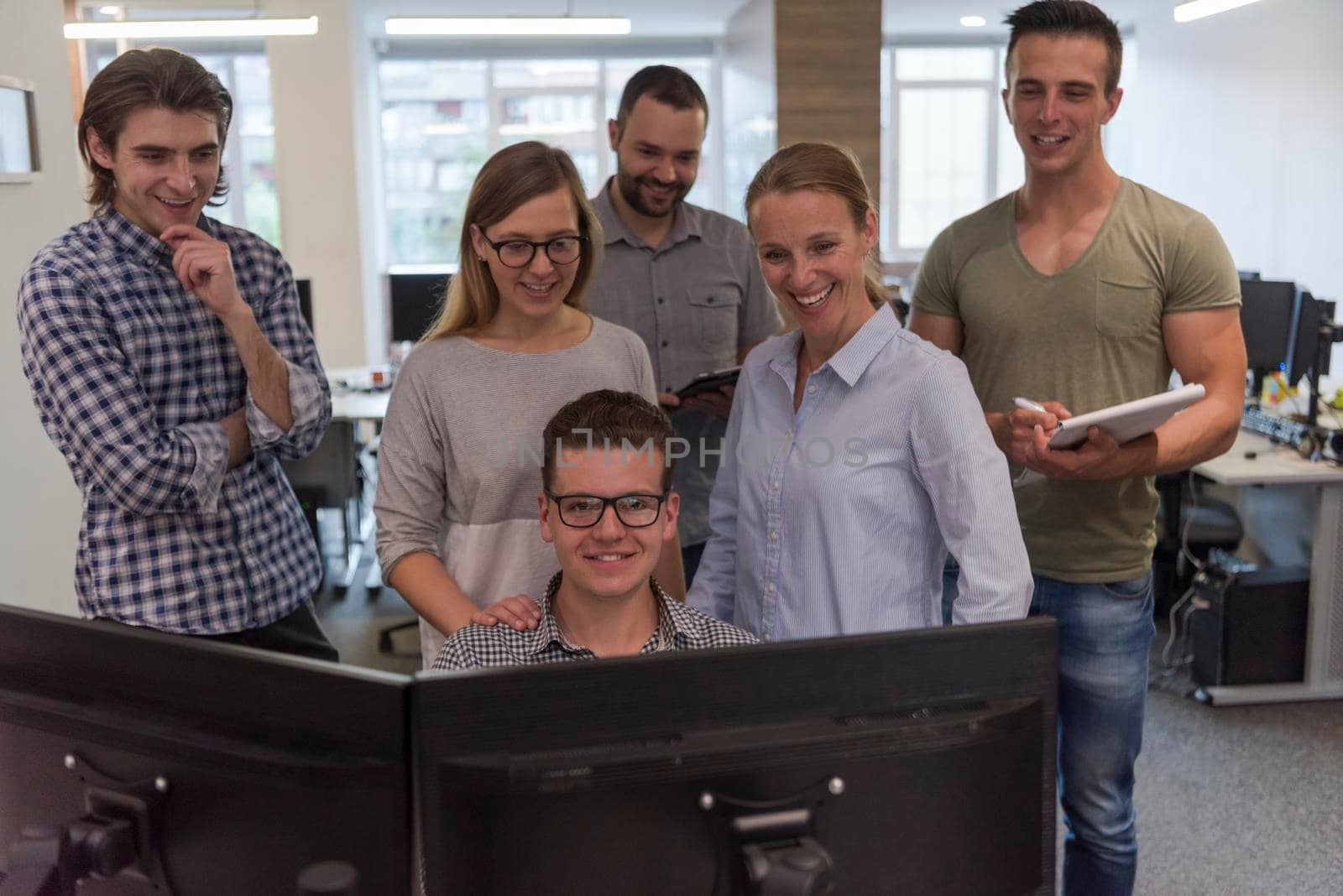 group of young startup business people standing as team at office desk while working on everyday job