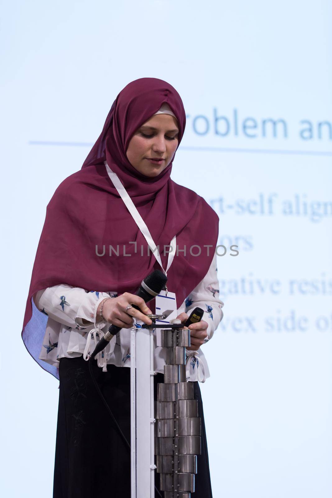 young muslim businesswoman with red scarf at business conference room giving public presentations. Audience at the conference hall. Entrepreneurship club