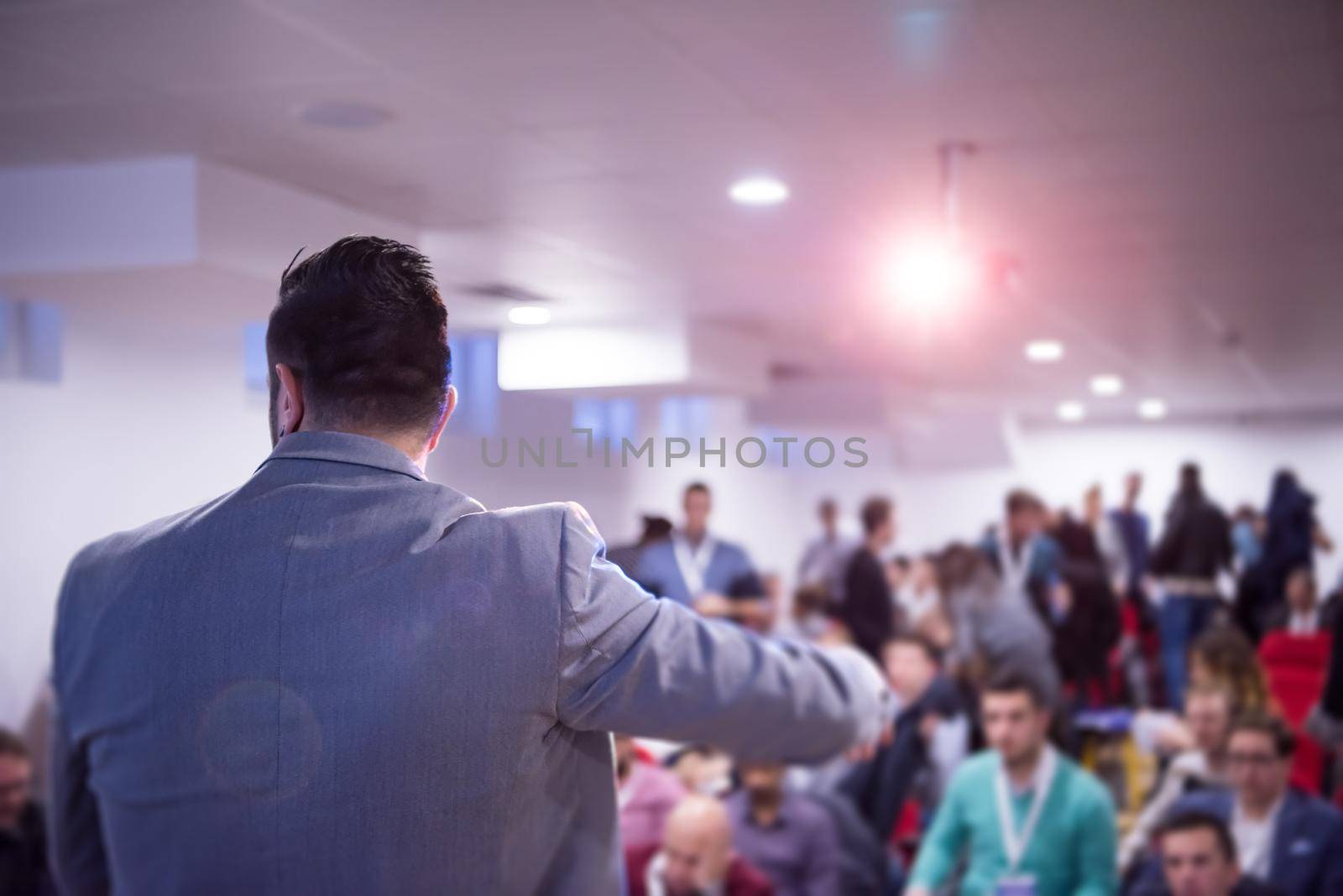 rear view of young successful businessman at business conference room with public giving presentations. Audience at the conference hall. Entrepreneurship club
