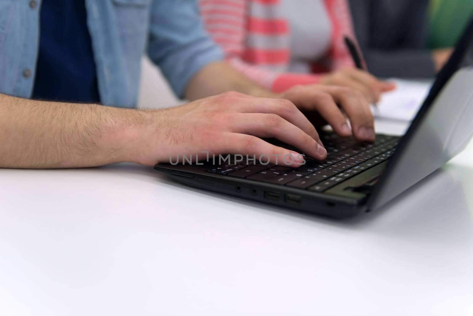 close up of student hands typing on laptop by dotshock