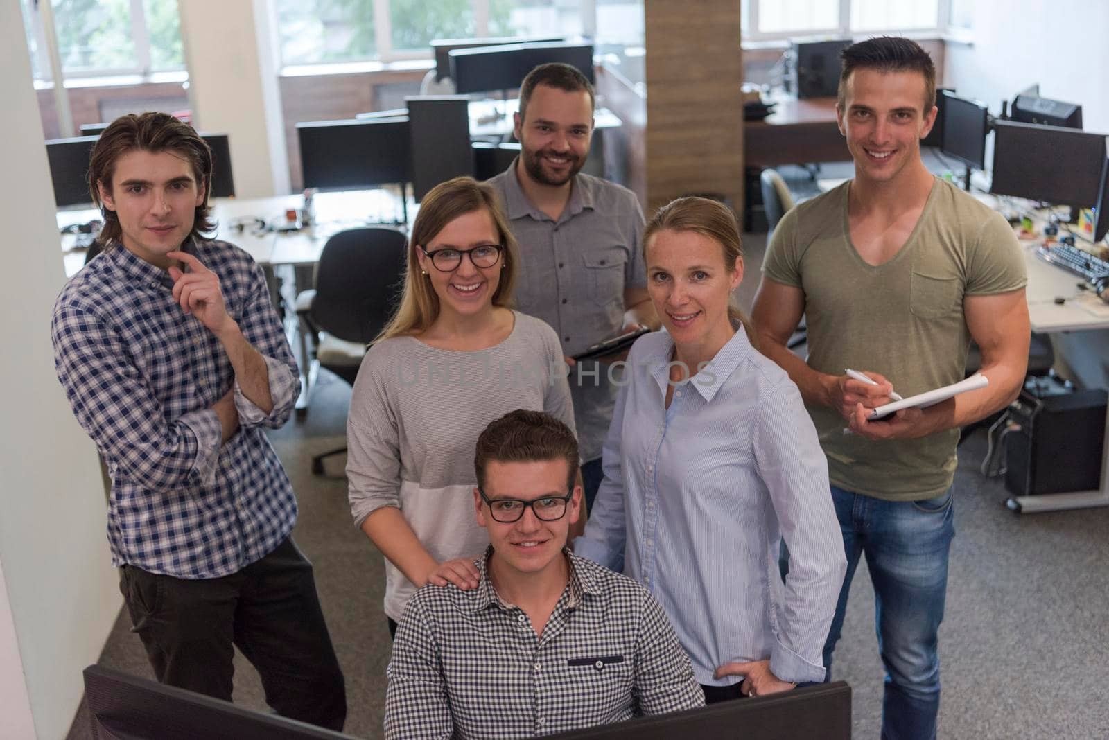 group of young startup business people standing as team at office desk while working on everyday job