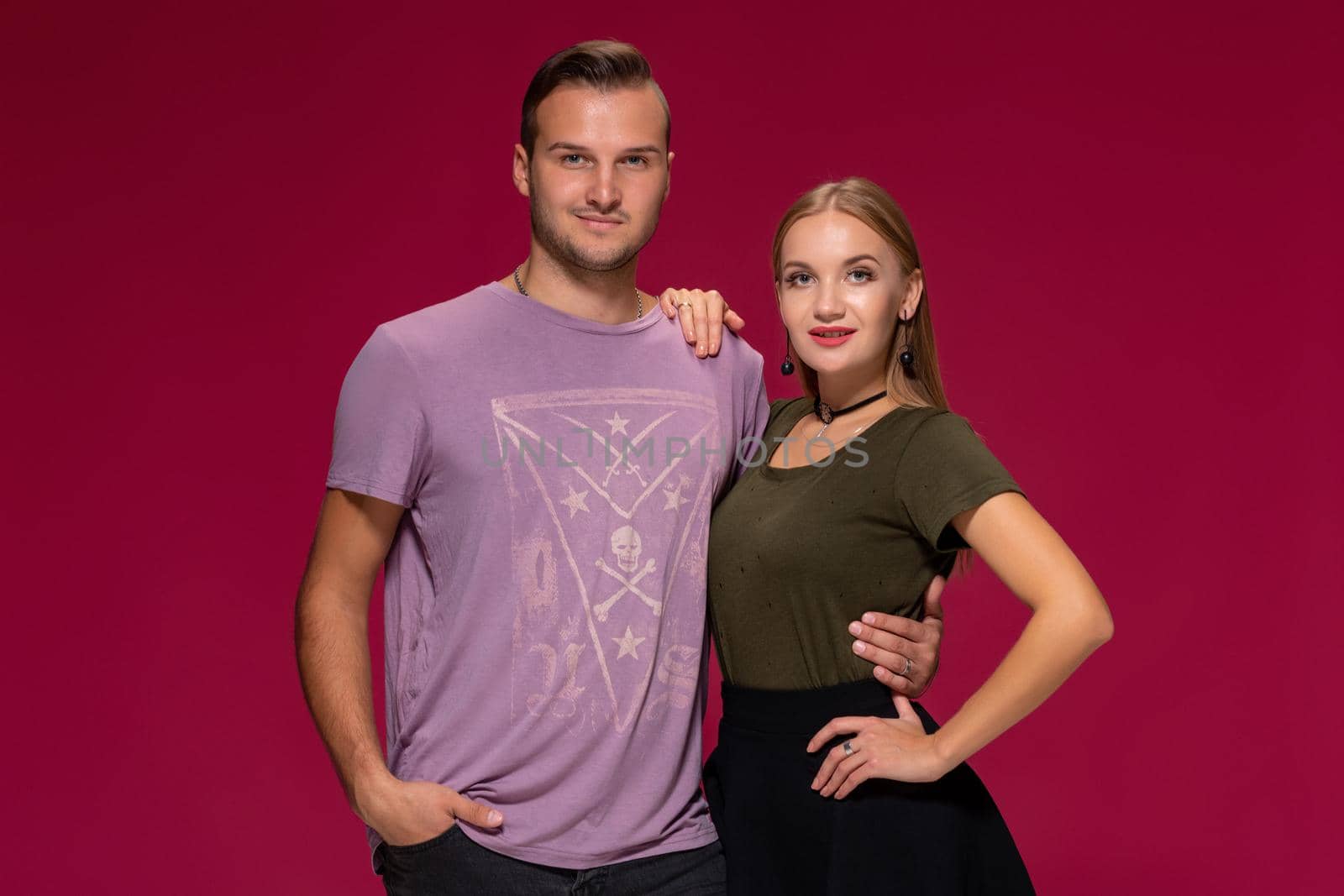 Young nice couple posing in the studio, express emotions and gestures, smiling, on a burgundy background by nazarovsergey