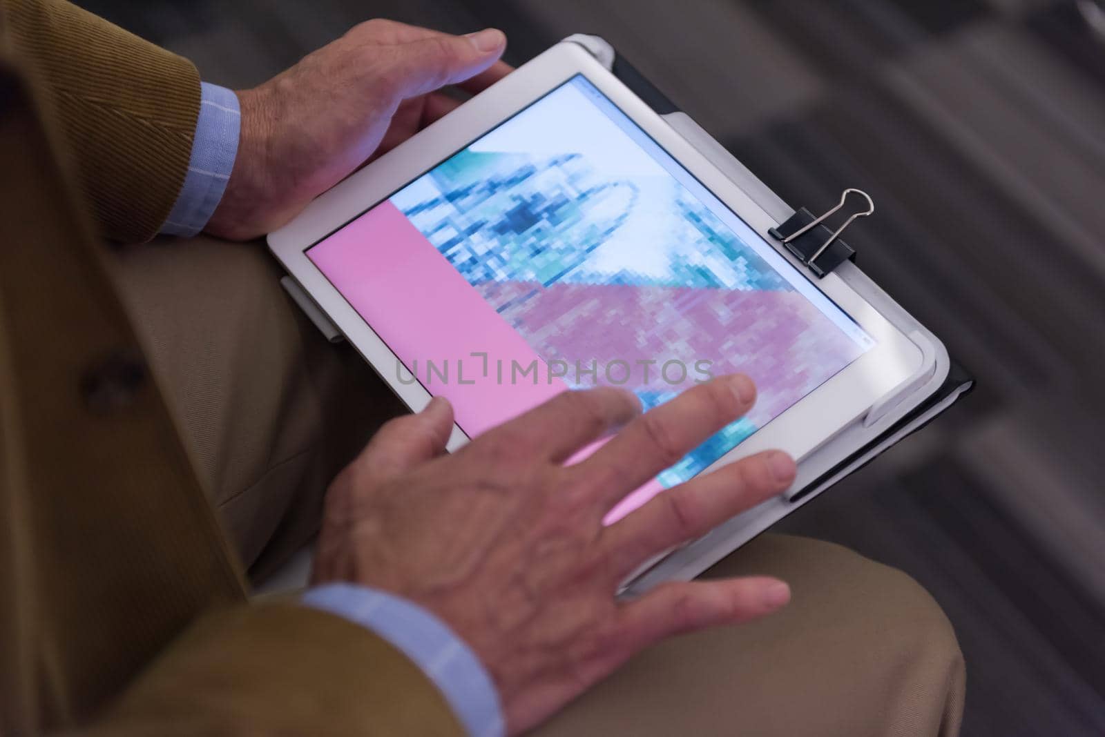 Closeup of mature hands holding tablet. Teacher with students in classroom