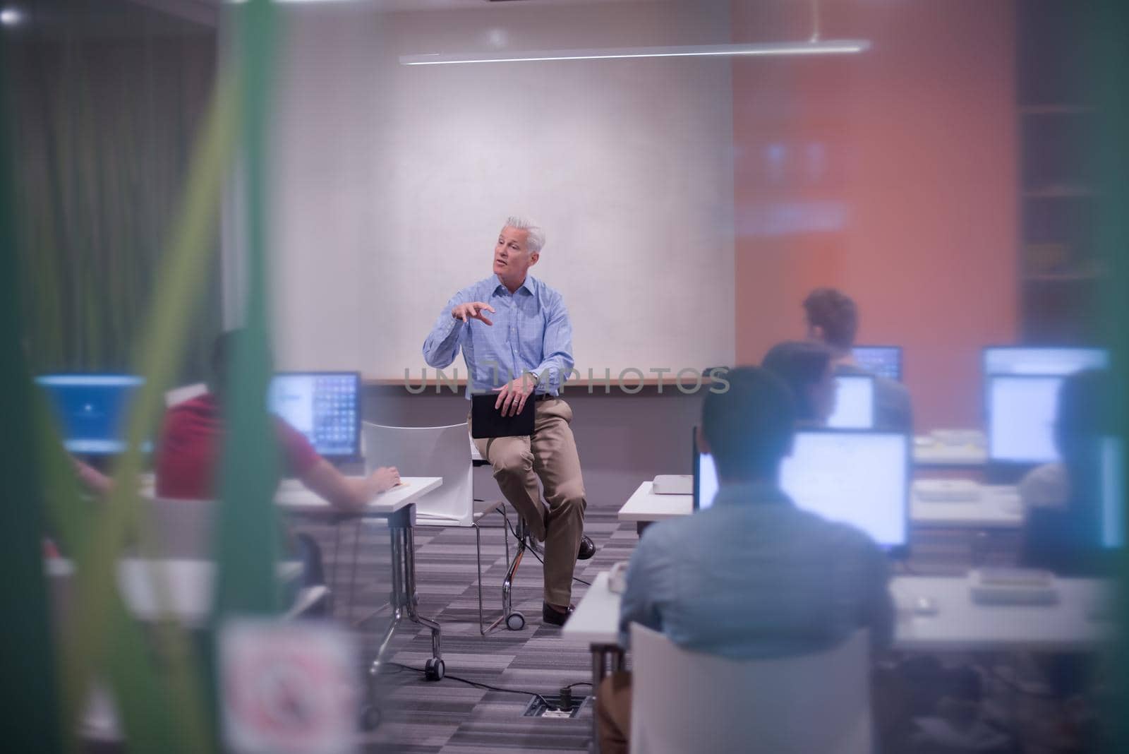 handsome mature teacher and students in computer lab classroom