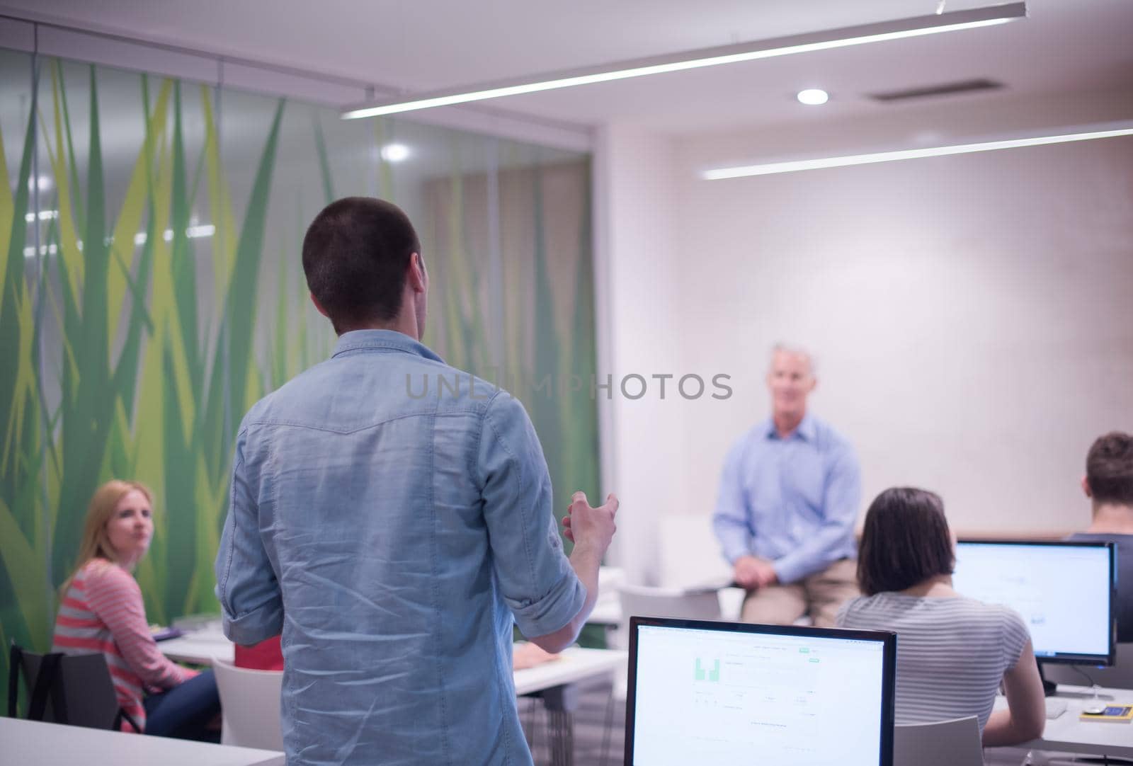 student answering a question in classroom, mature teacher and students in computer lab classroom