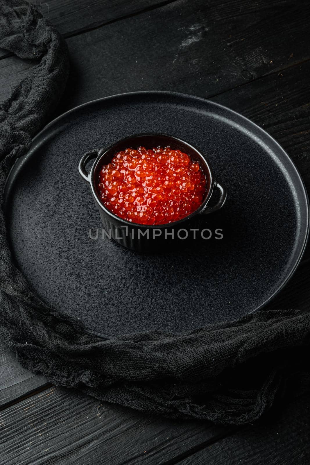 Red salmon caviar in bowl, on black wooden table background