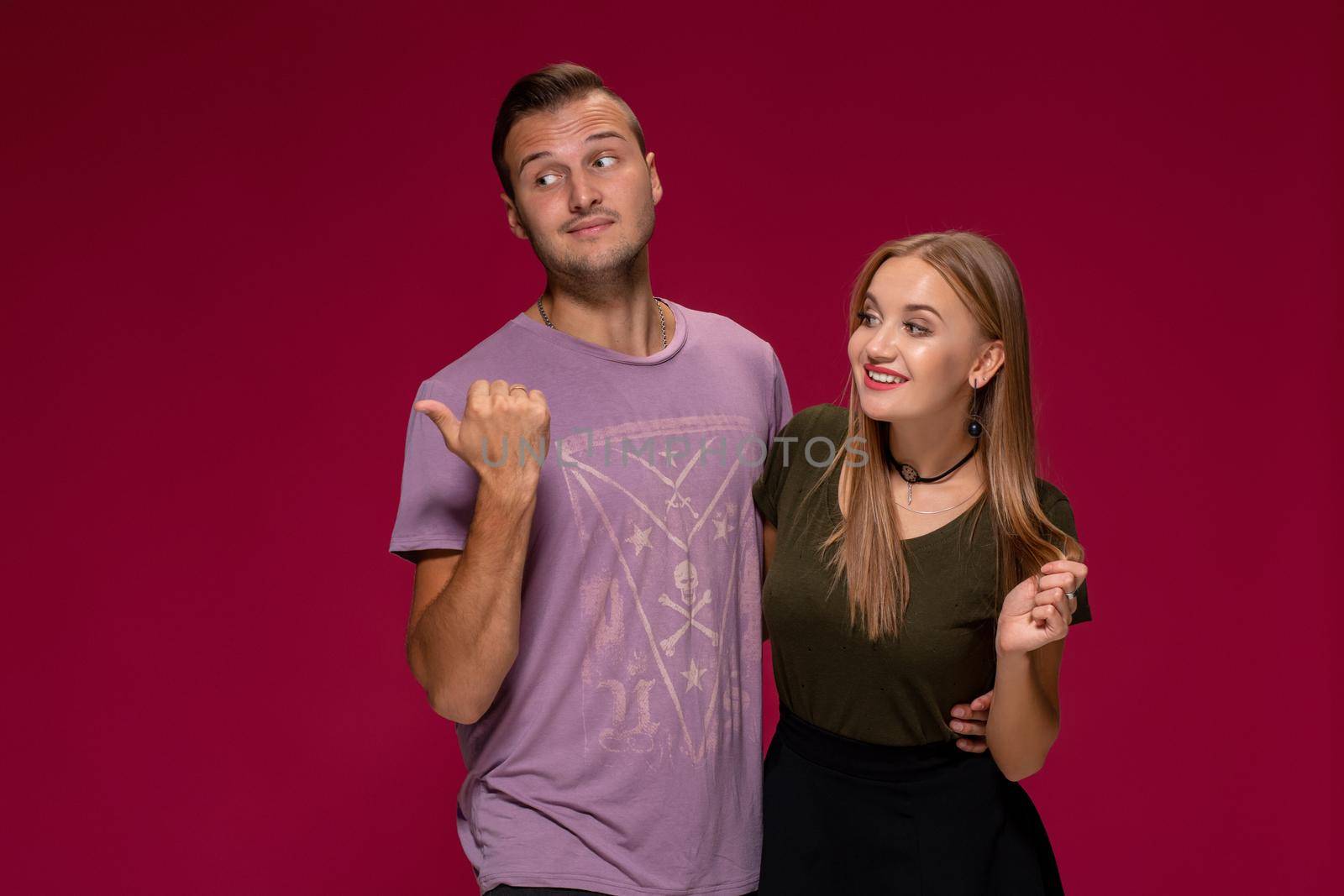 People, friendship, love and leisure concept - lovely couple with thumbs-up gesture on burgundy background with copy space for your advertisement or written text.