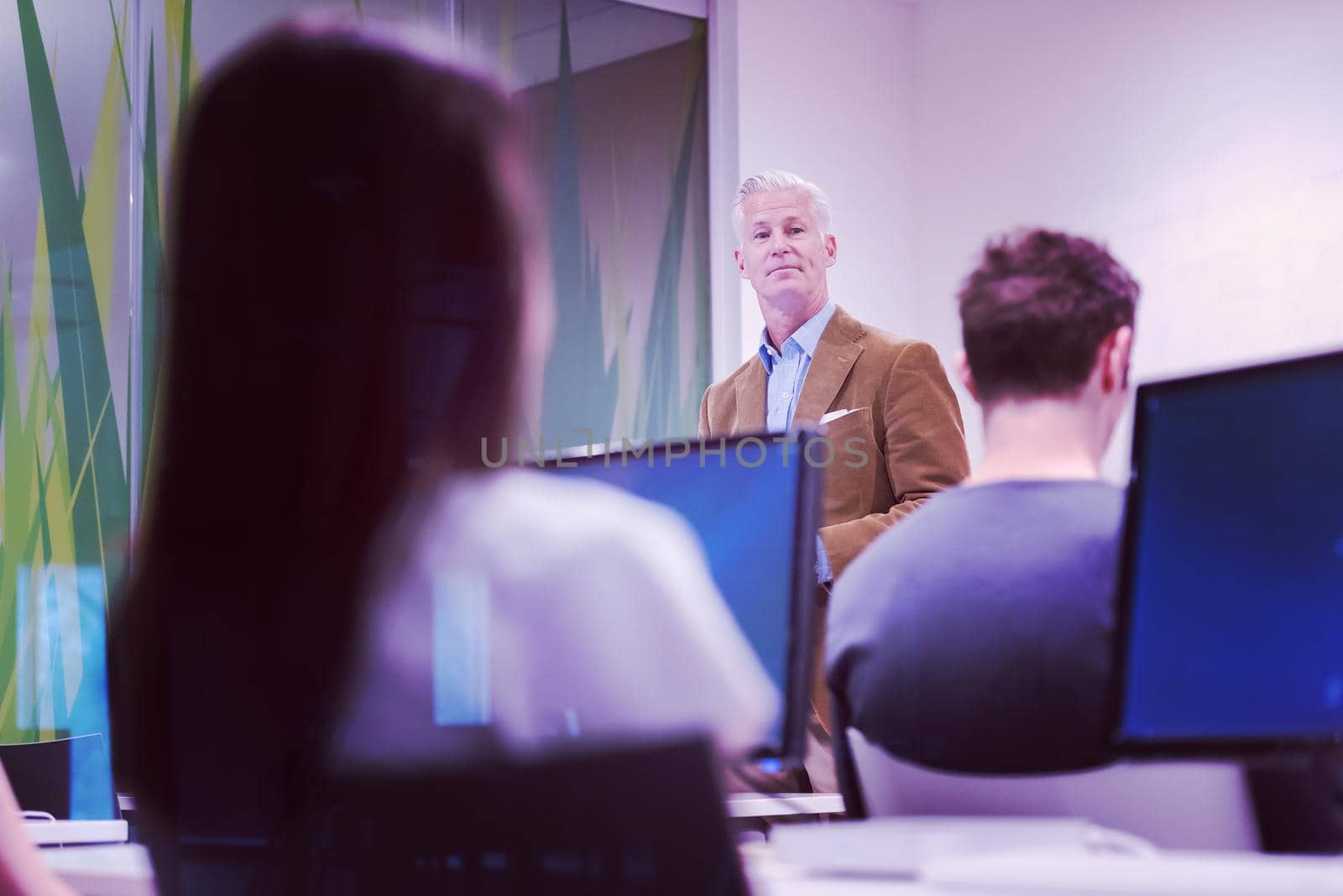 handsome mature teacher and students in computer lab classroom