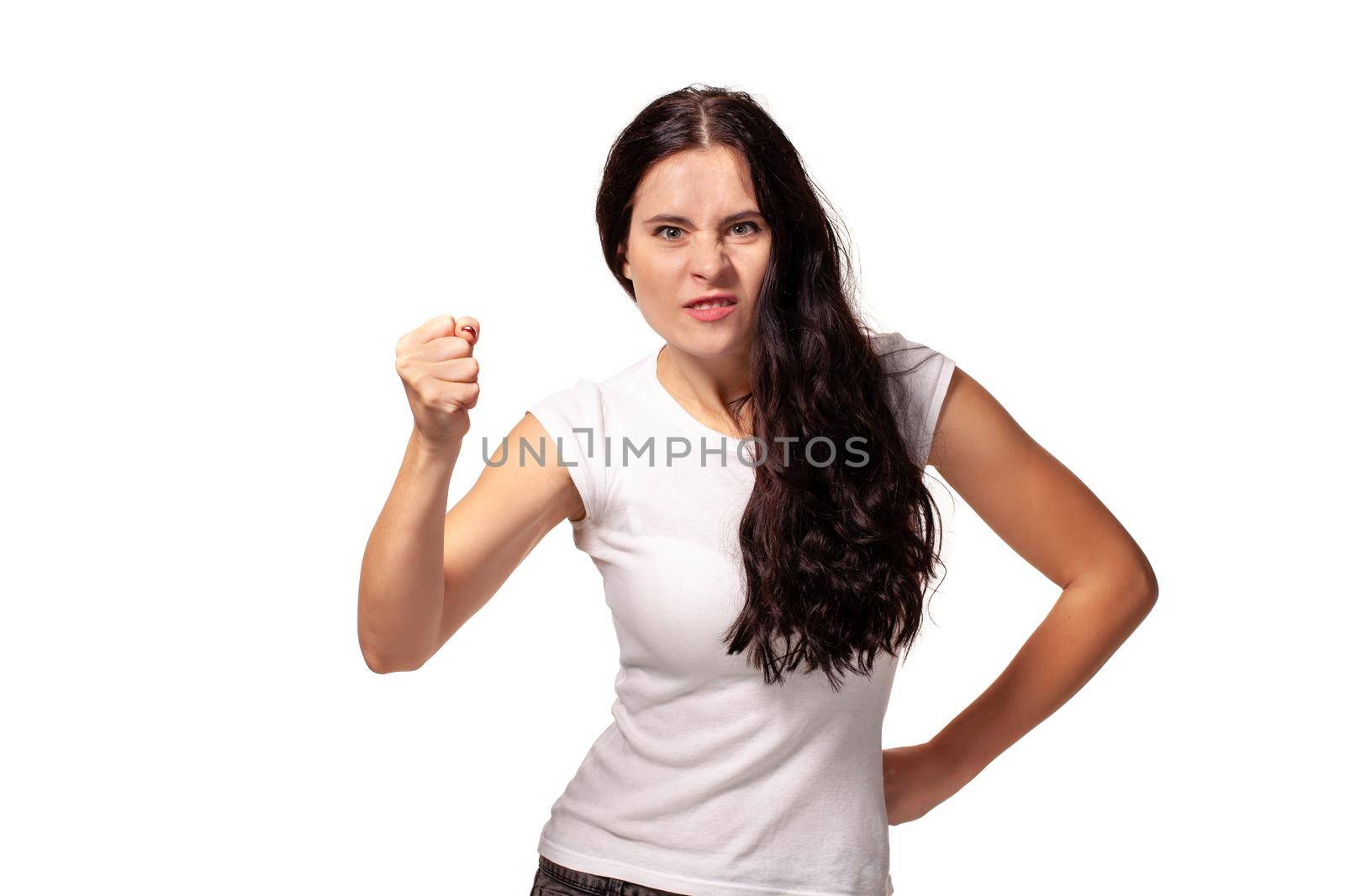 The portrait the young beautiful woman threatens with a fist is isolated on white
