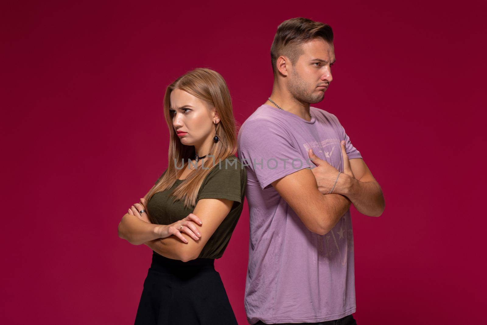 Studio portrait of a young couple in casual wear quarreled and taking a step towards reconciliation. The problem of relationships, quarrels, difficulties in communication